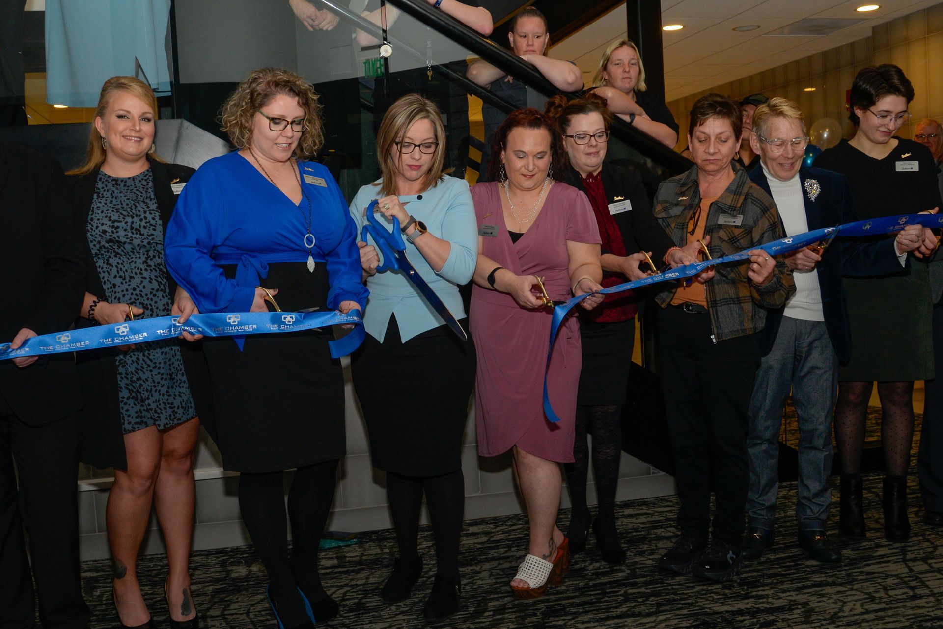 A group of women are cutting a blue ribbon