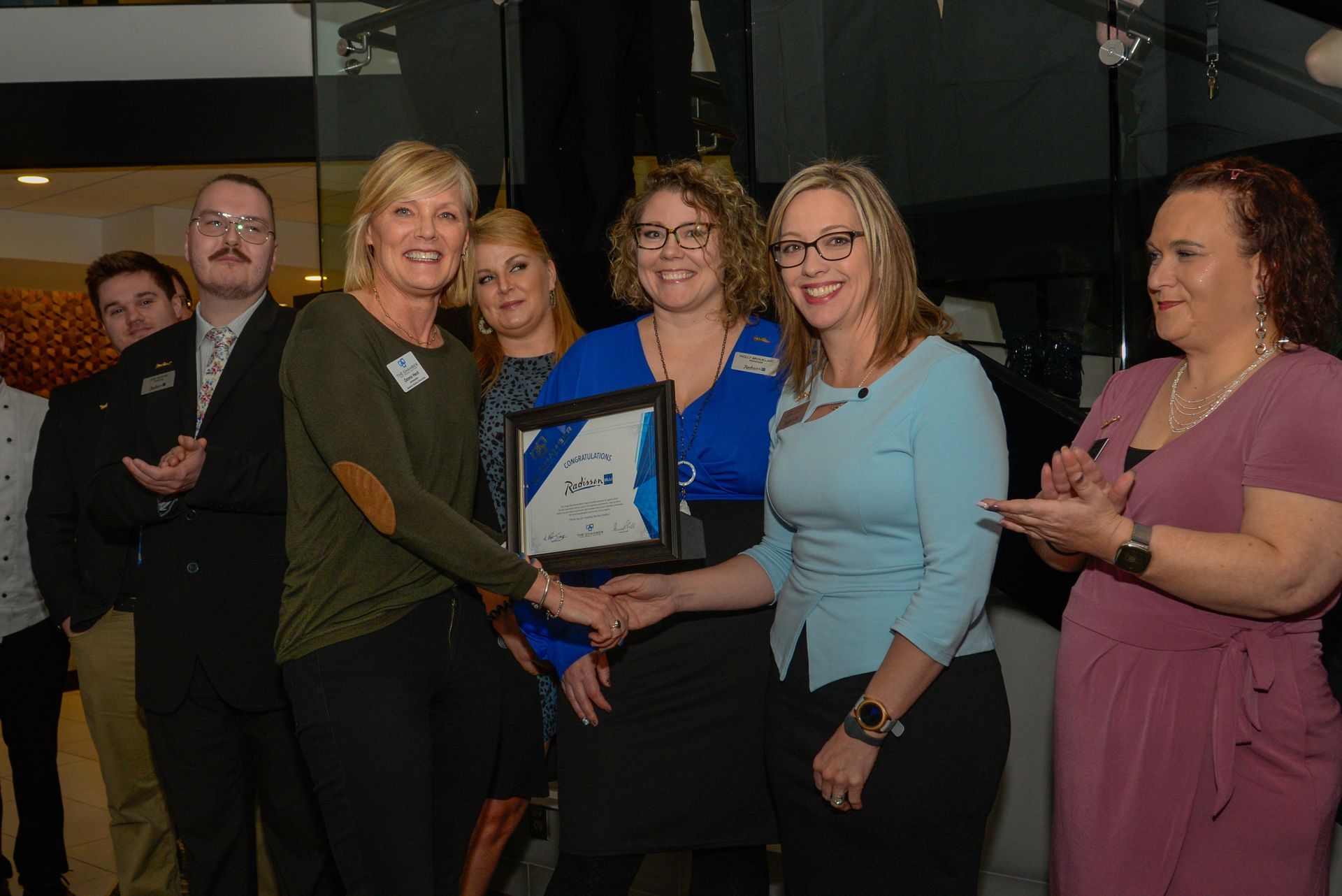A group of women standing around a woman holding a certificate