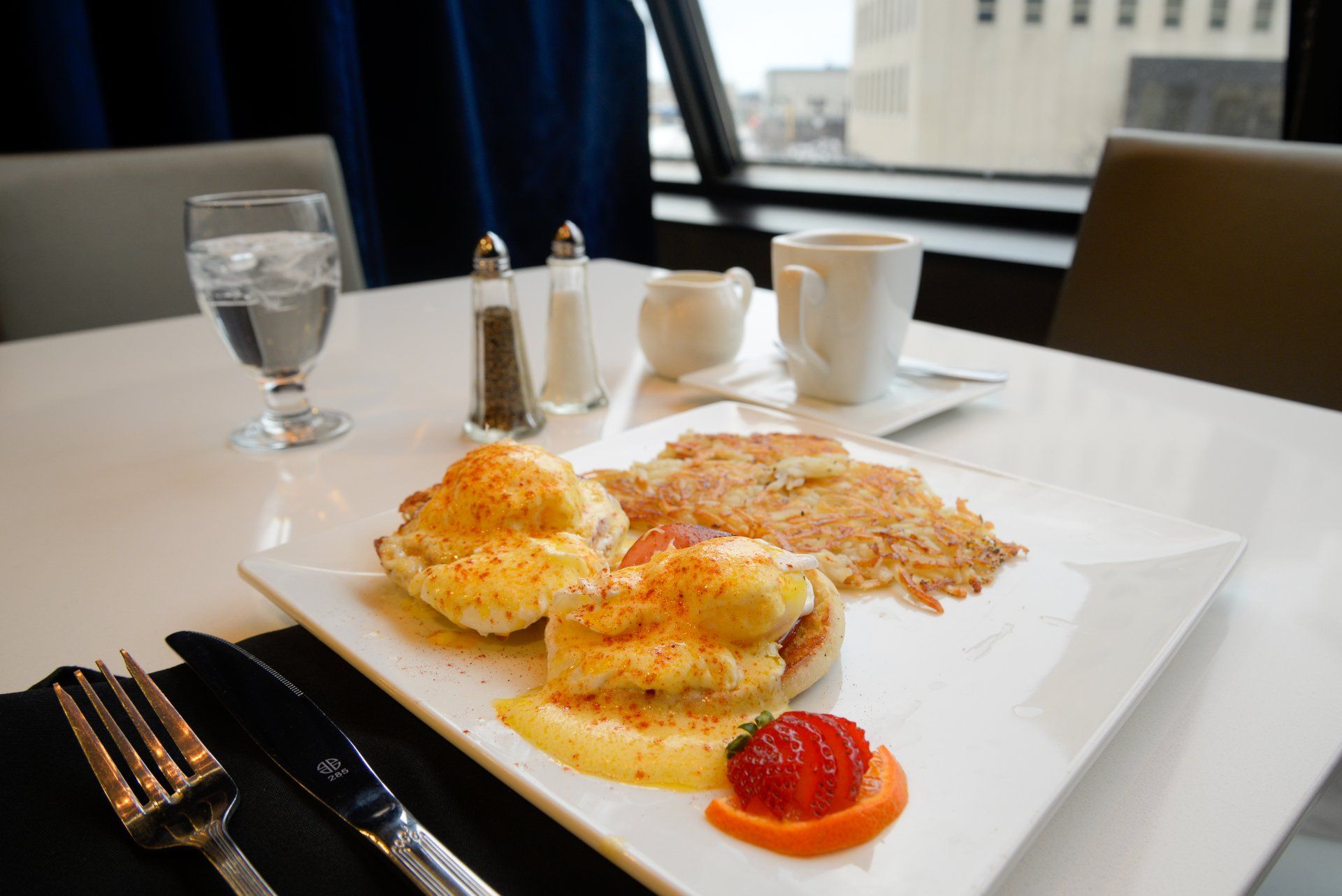 A plate of food with eggs benedict and hash browns on a table
