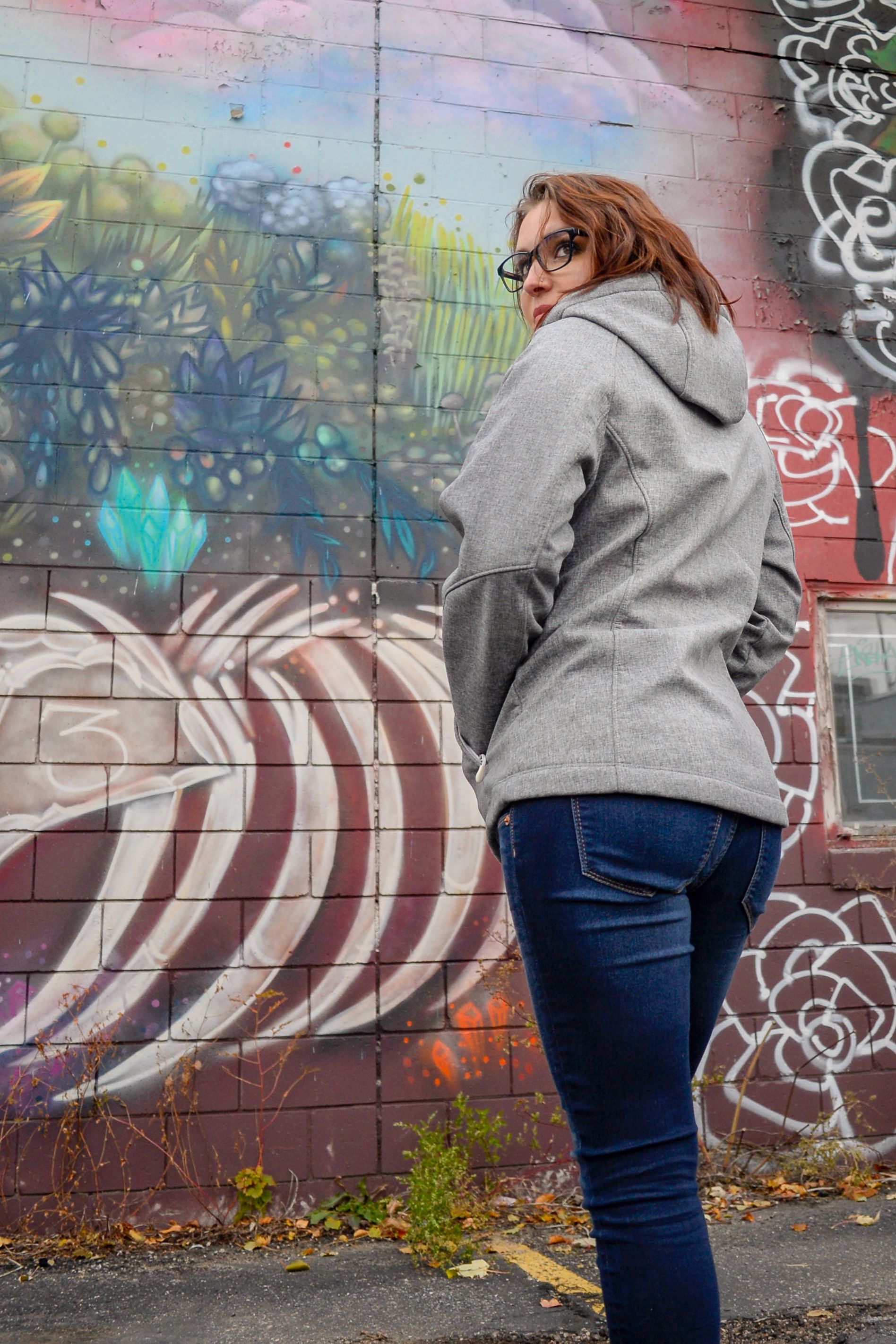 A woman standing in front of a wall with graffiti on it