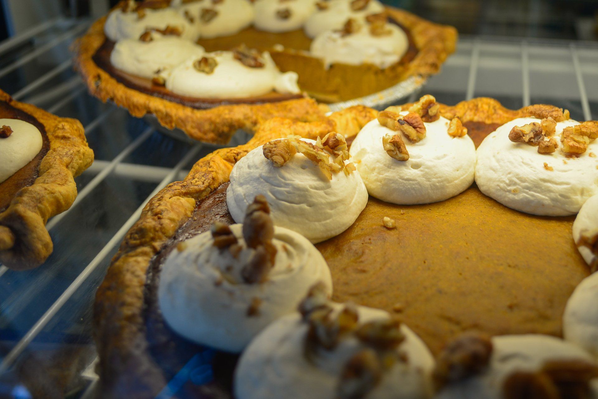 A pumpkin pie with whipped cream and pecans on top