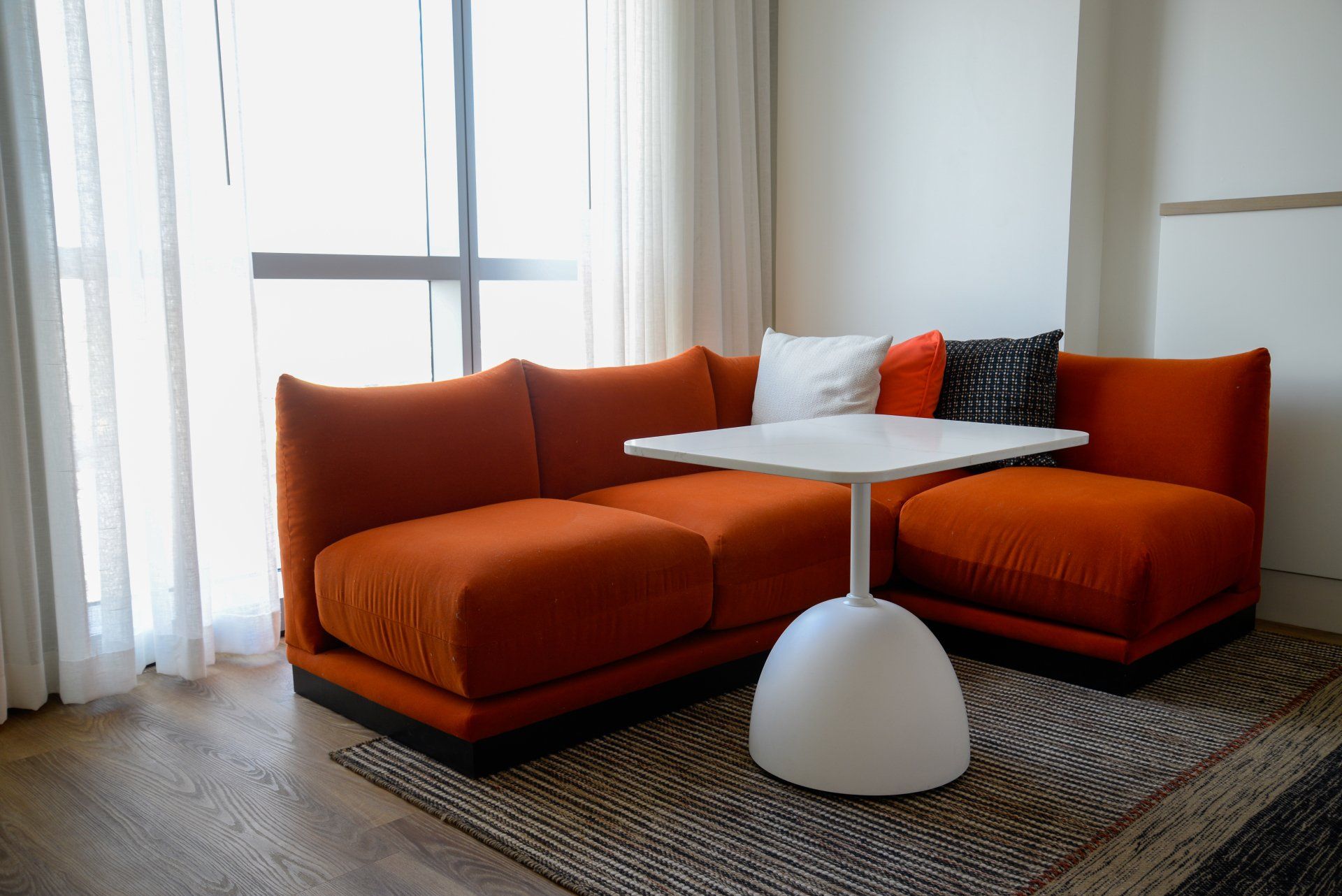 A living room with an orange couch and a white table