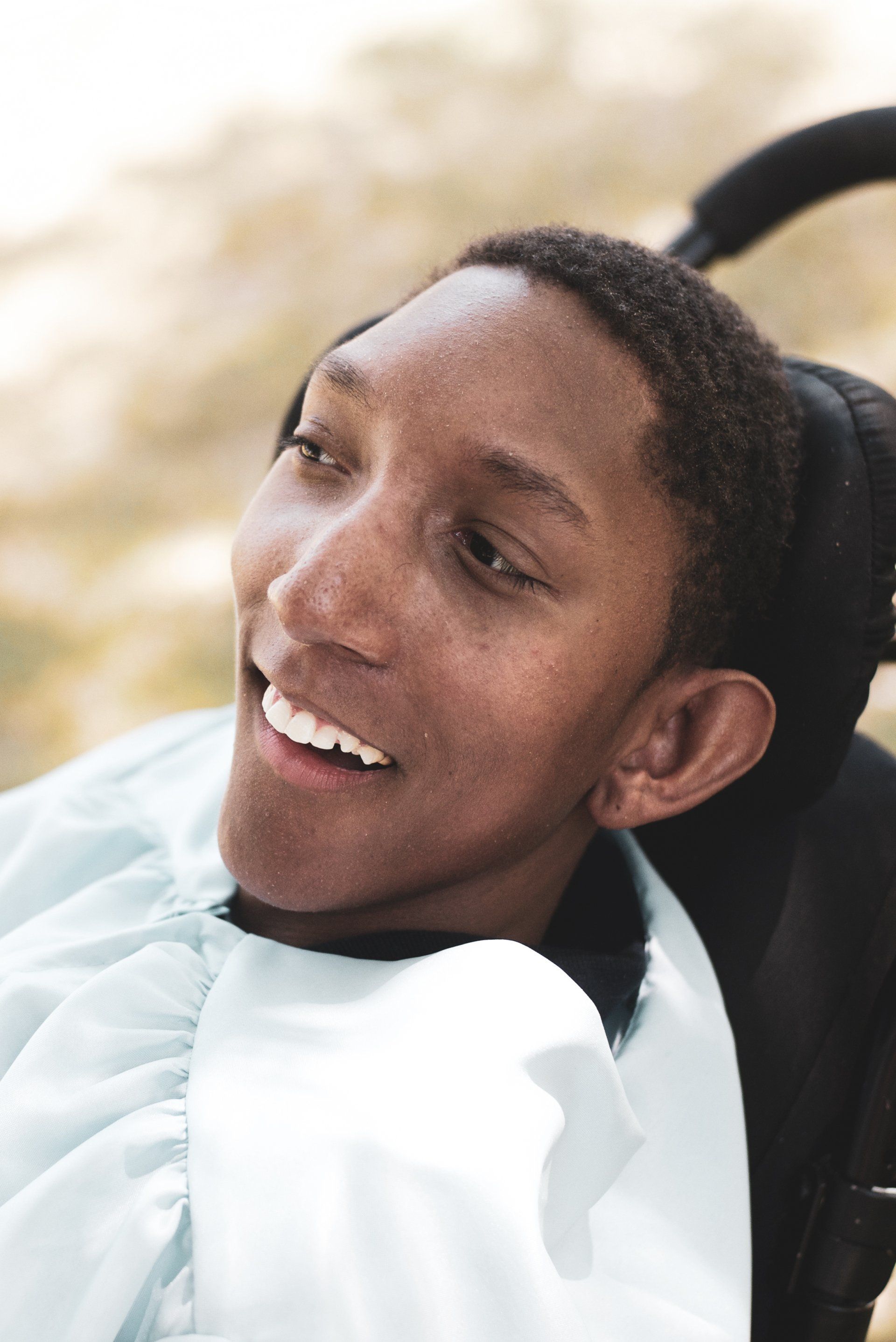 A young man in a wheelchair is smiling for the camera