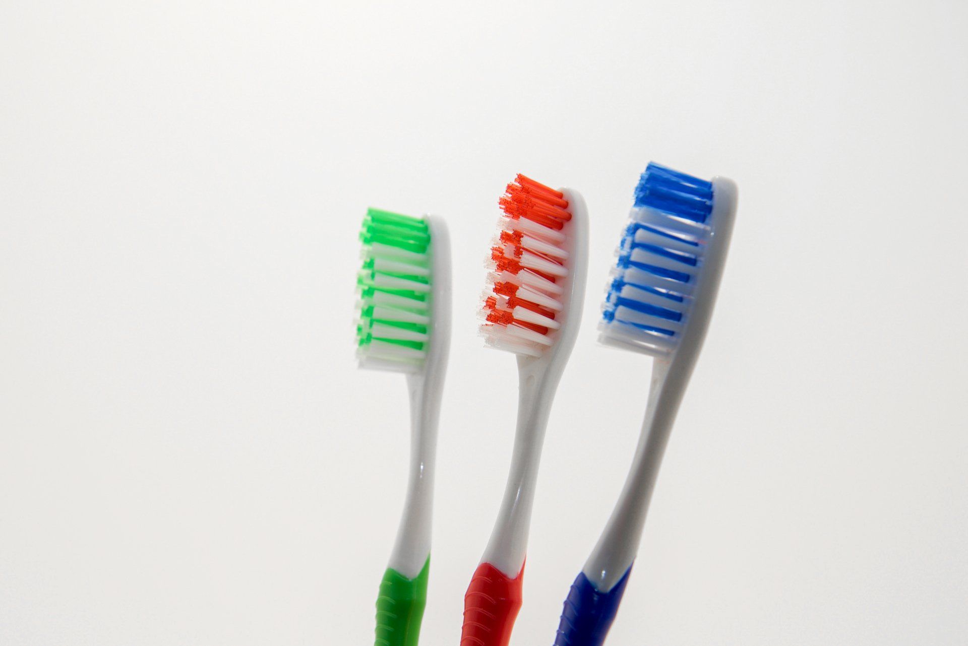 Three different colored toothbrushes on a white background