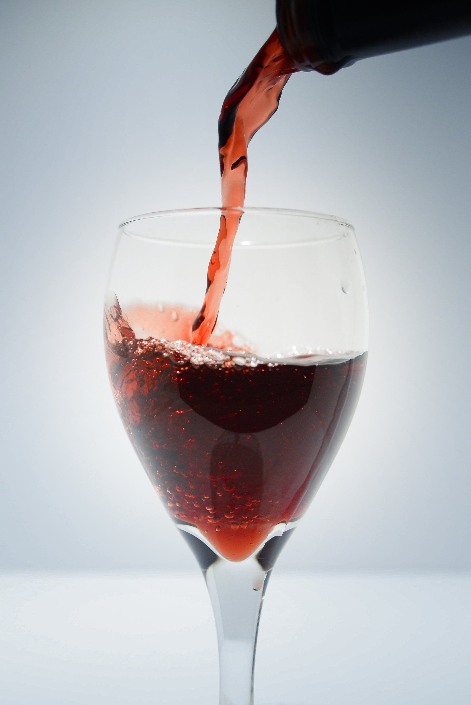 A glass of red wine is being poured from a bottle