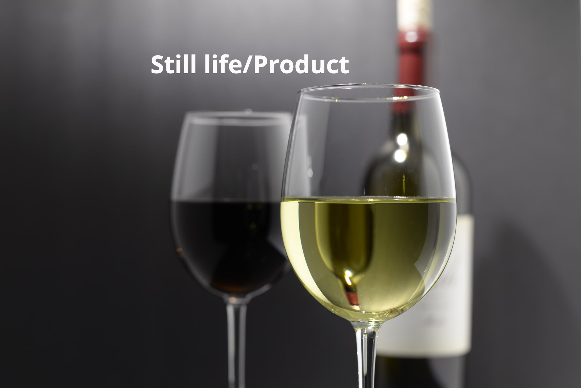 A bottle of wine sits next to two glasses of wine