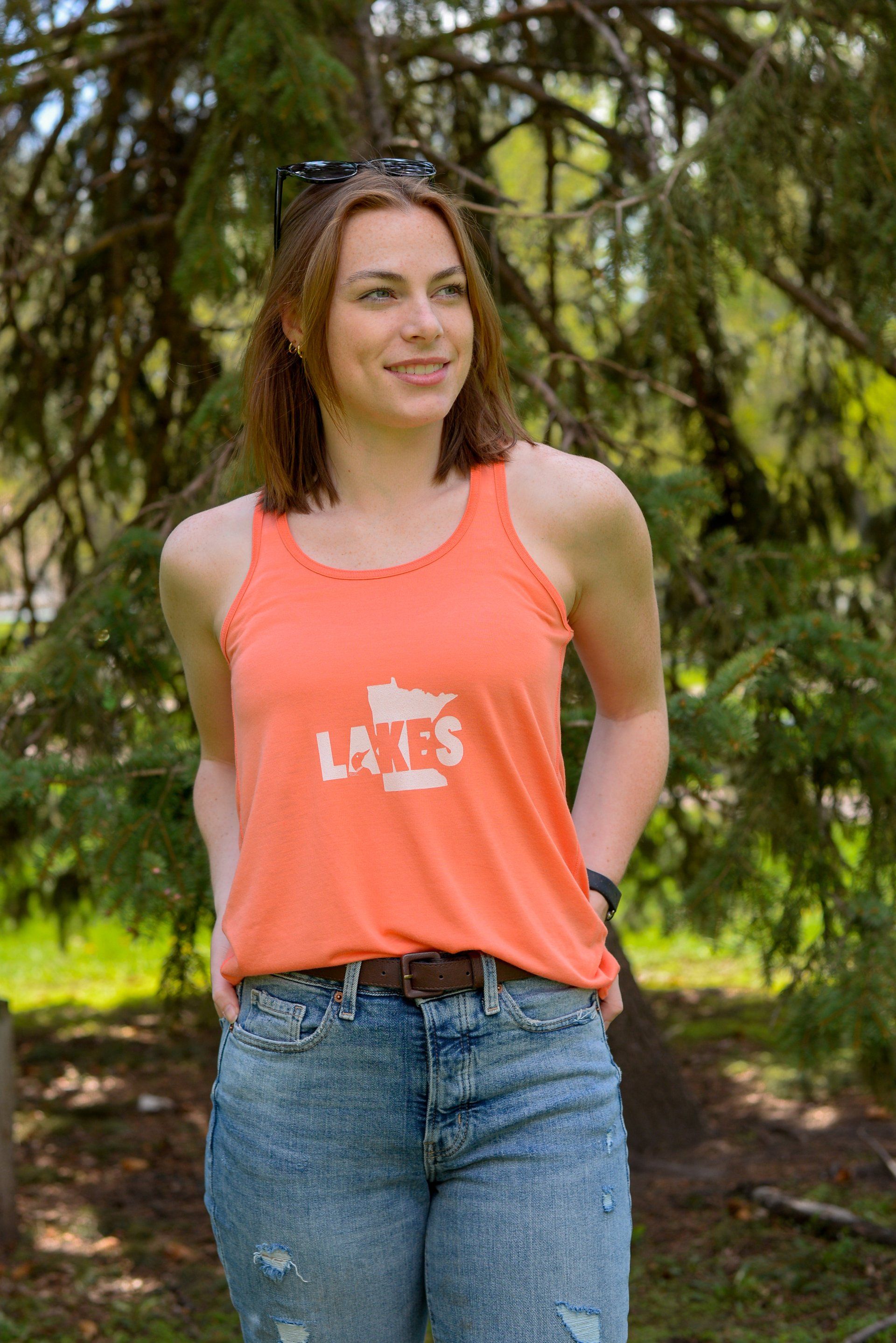 A woman wearing an orange tank top with the word la on it