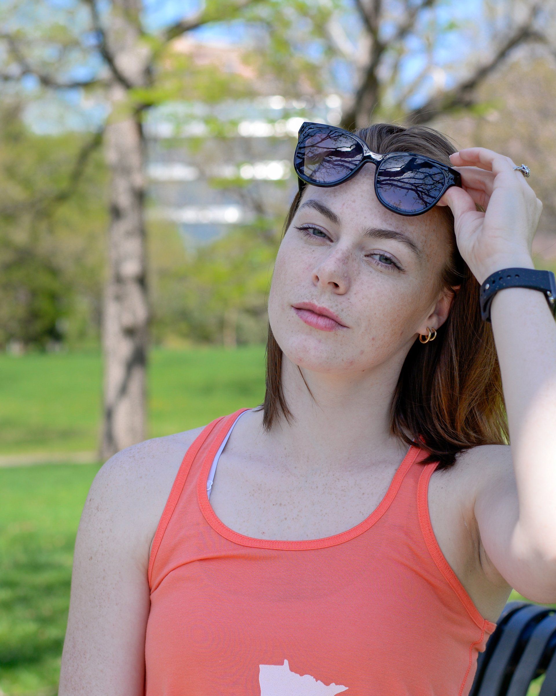 A woman wearing sunglasses and an orange tank top