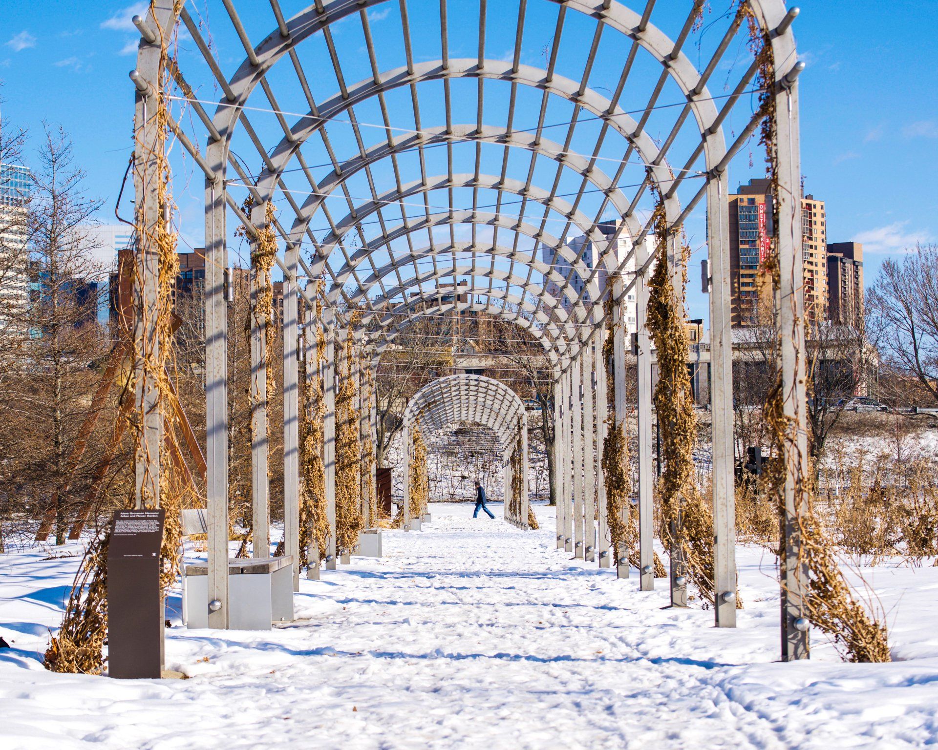 A person walking under a wooden archway in the snow