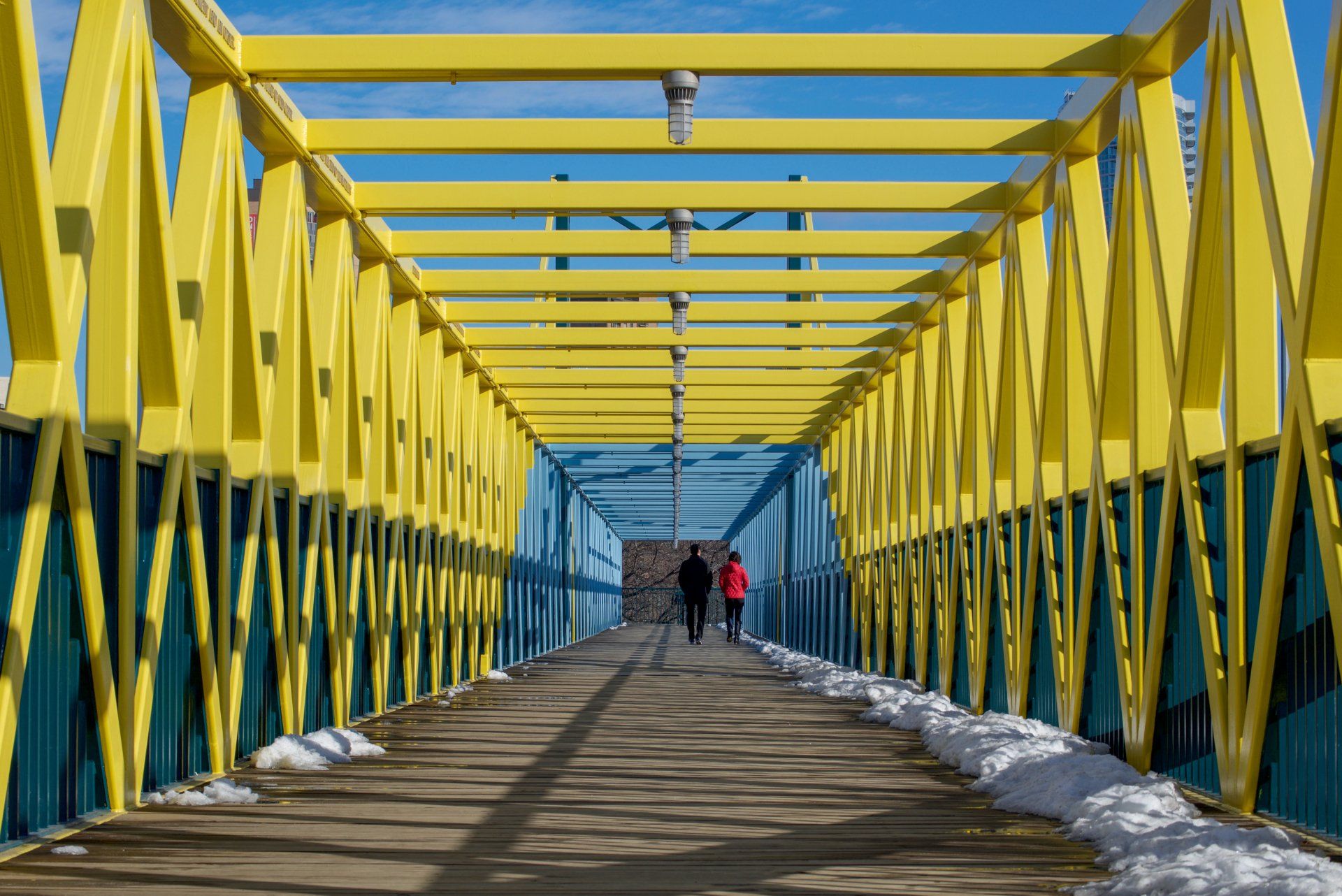 A couple walking across a yellow and blue bridge
