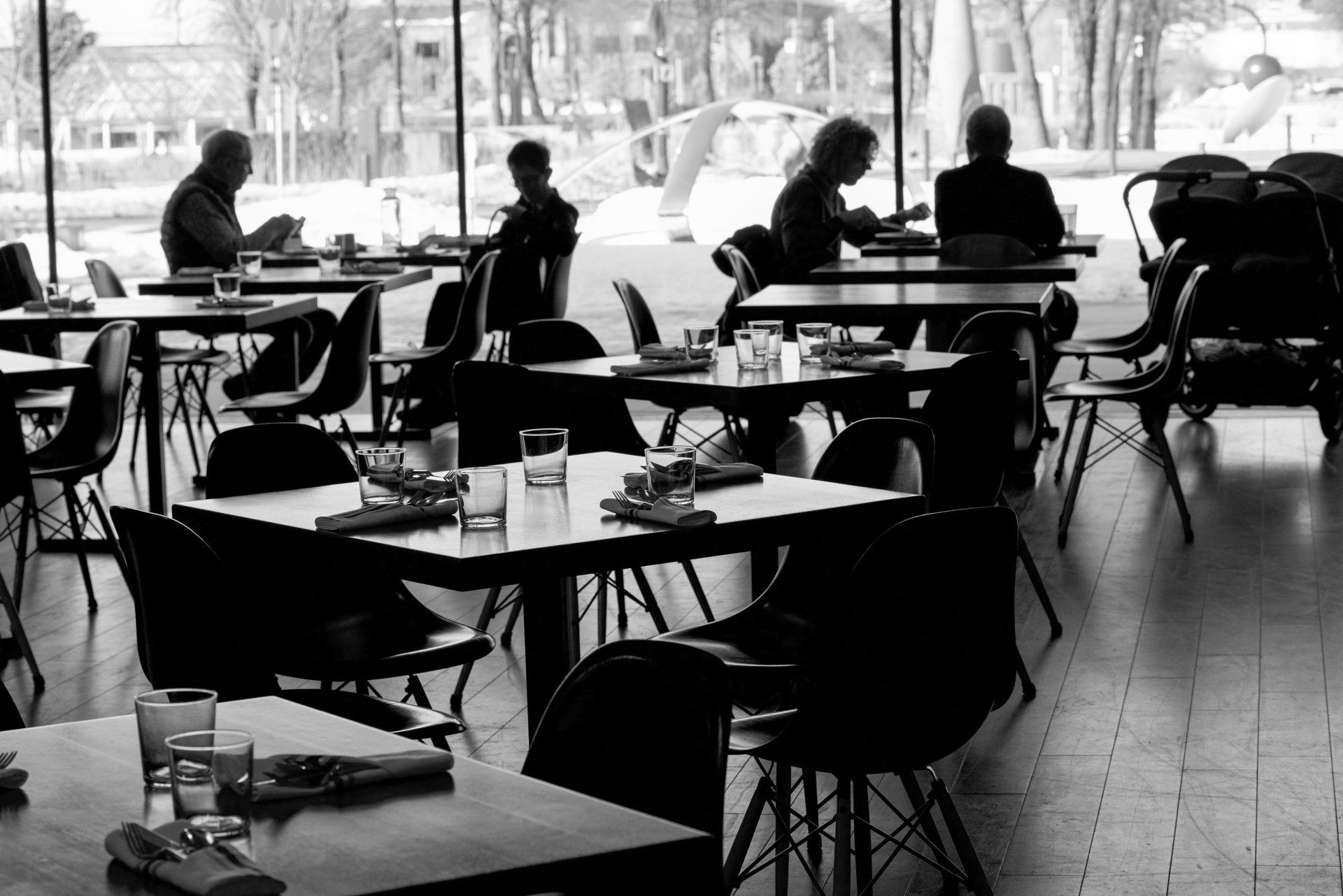 A black and white photo of people sitting at tables in a restaurant.