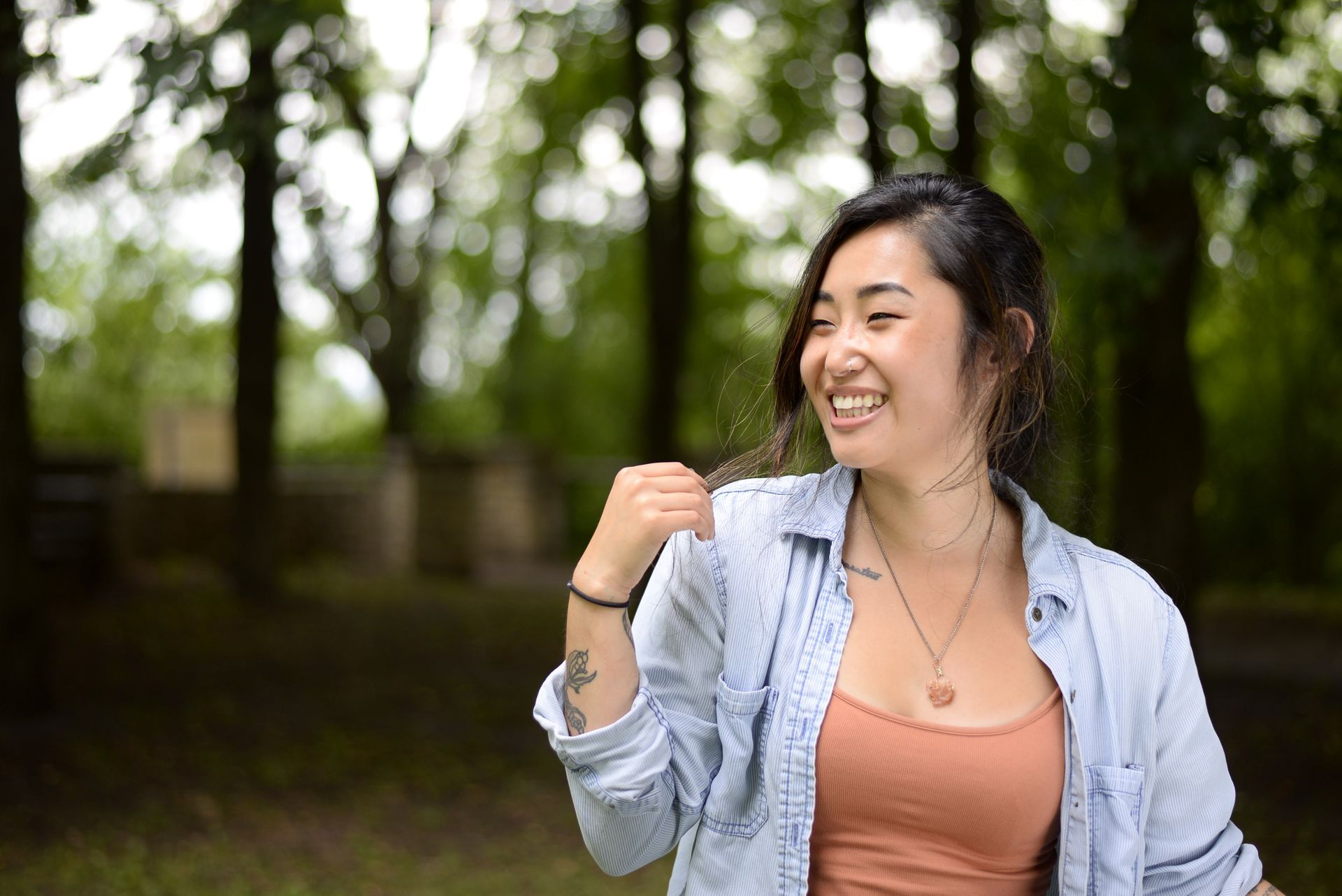 A woman with a tattoo on her arm is smiling in a park