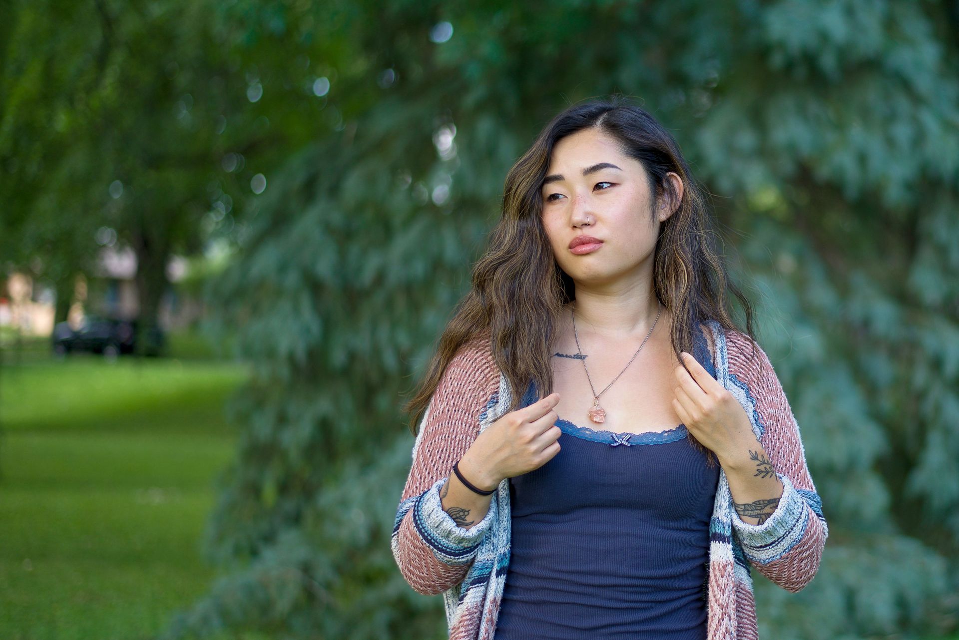 A woman is standing in front of a tree in a park.
