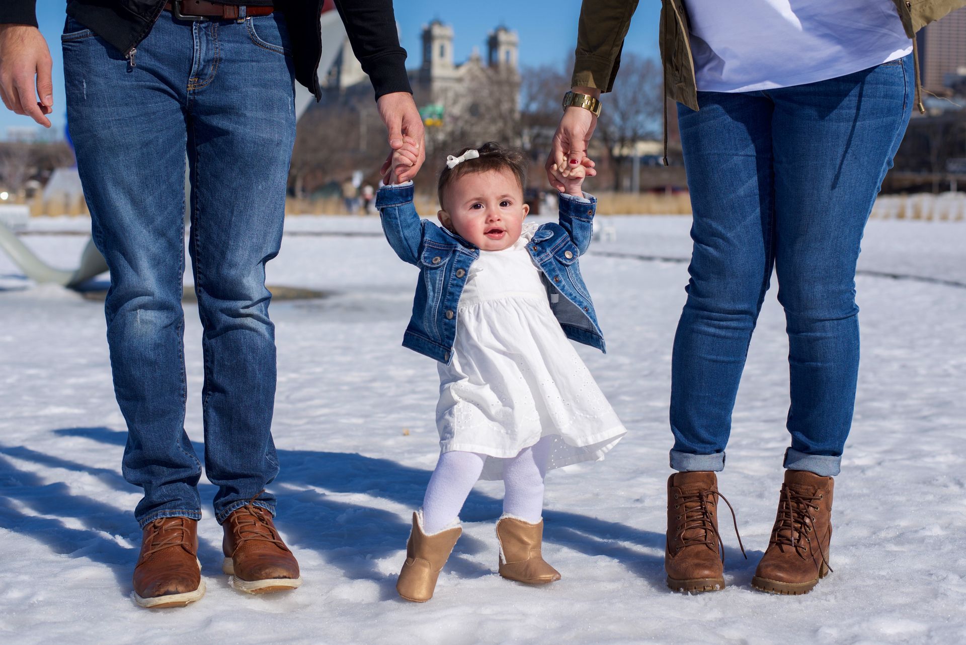A little girl is walking with her parents in the snow