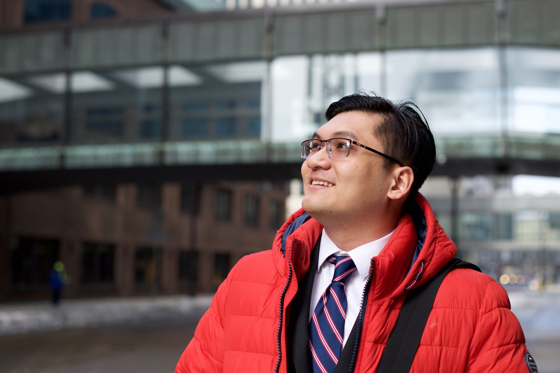 A man in a red jacket and tie is looking up