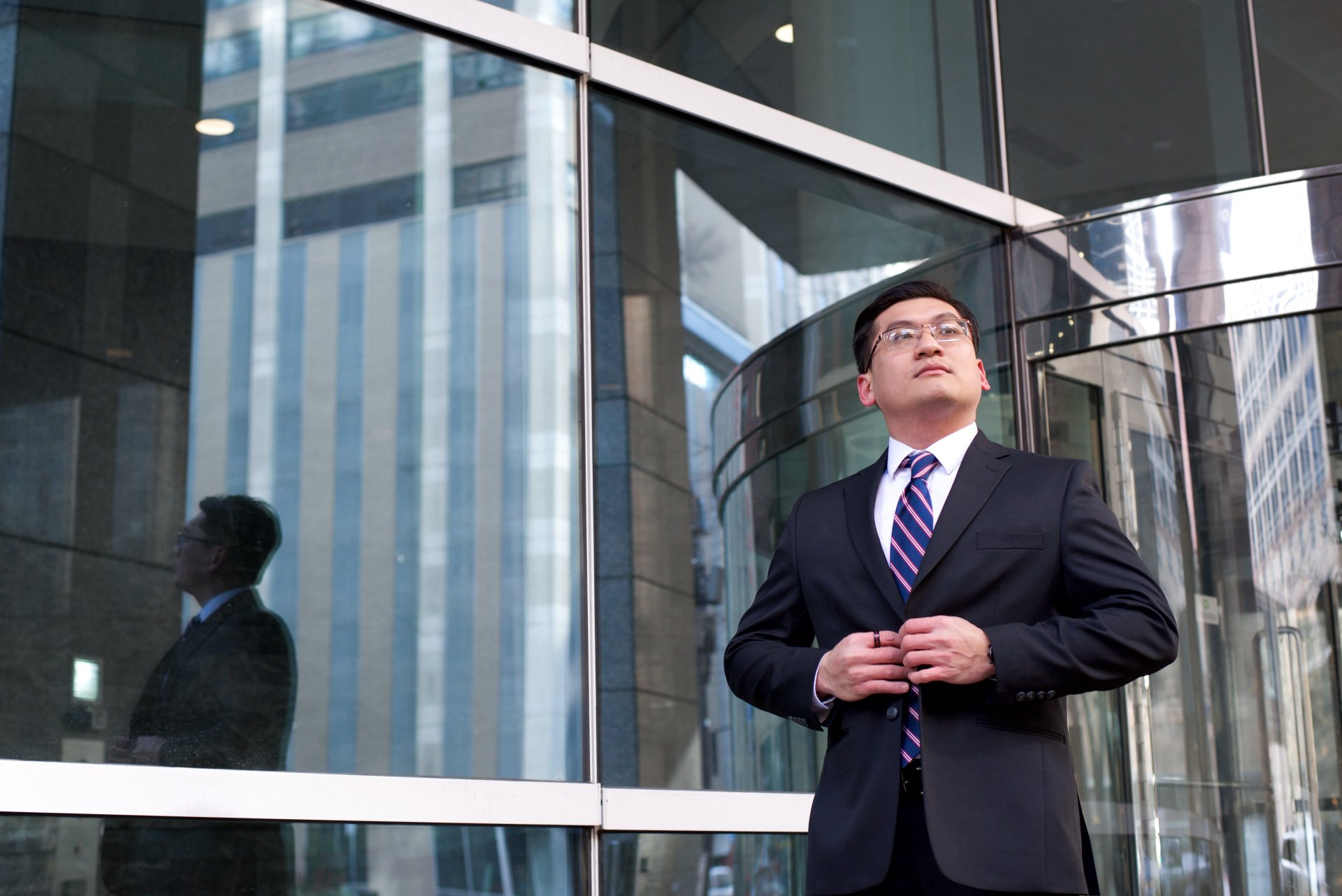 A man in a suit and tie is standing in front of a building