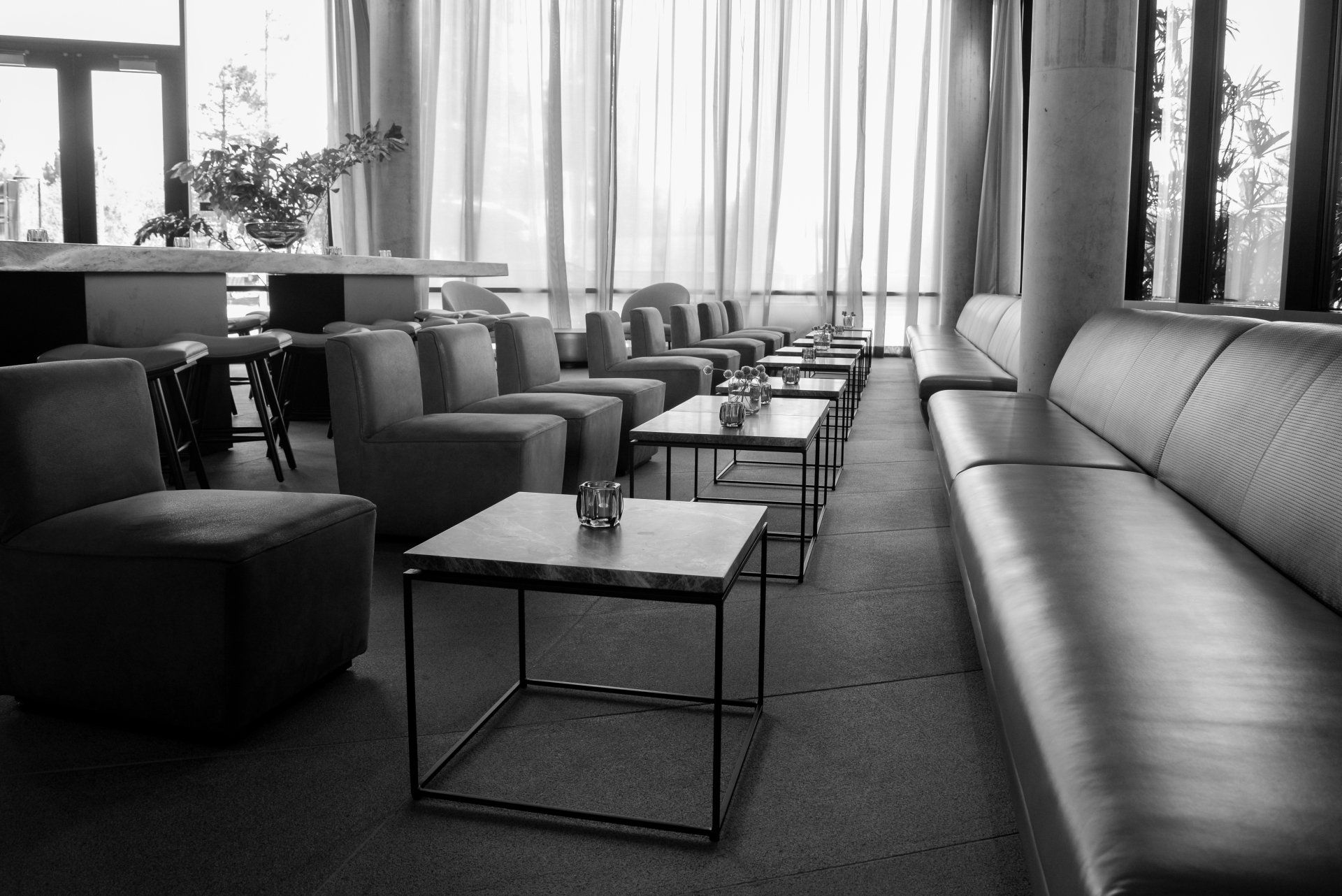 A black and white photo of a living room with tables and chairs
