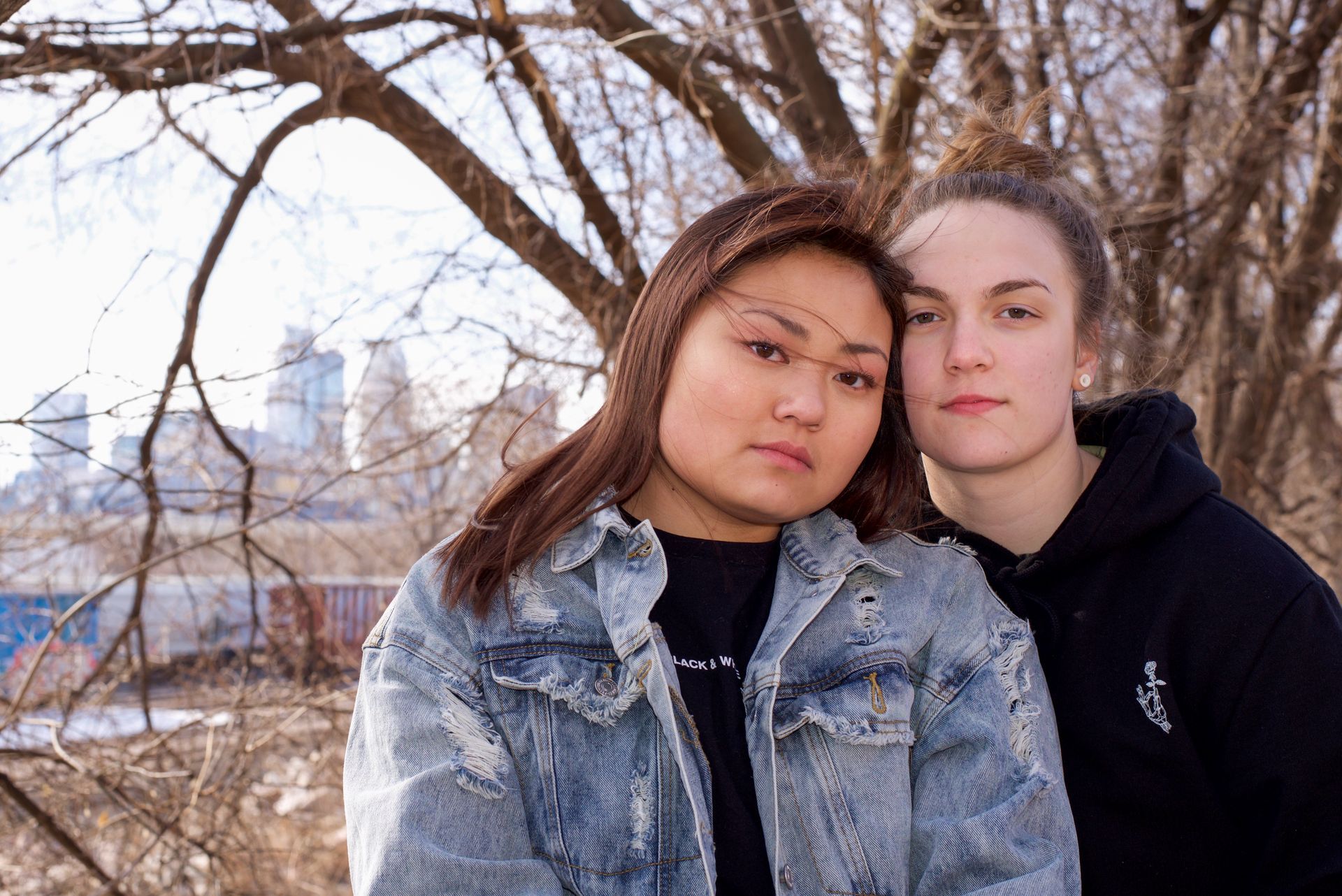 Two women are posing for a picture in front of a tree
