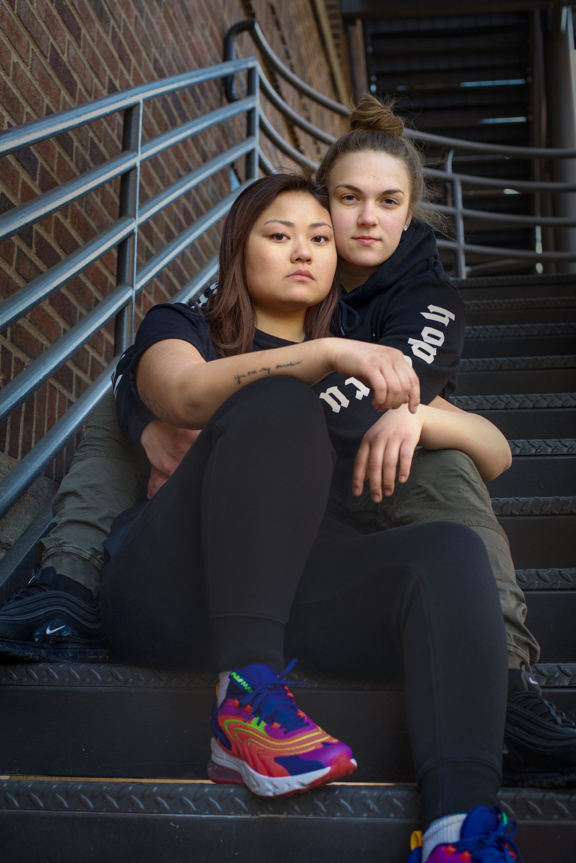 Two women sitting on a set of stairs with one wearing a shirt that says do it