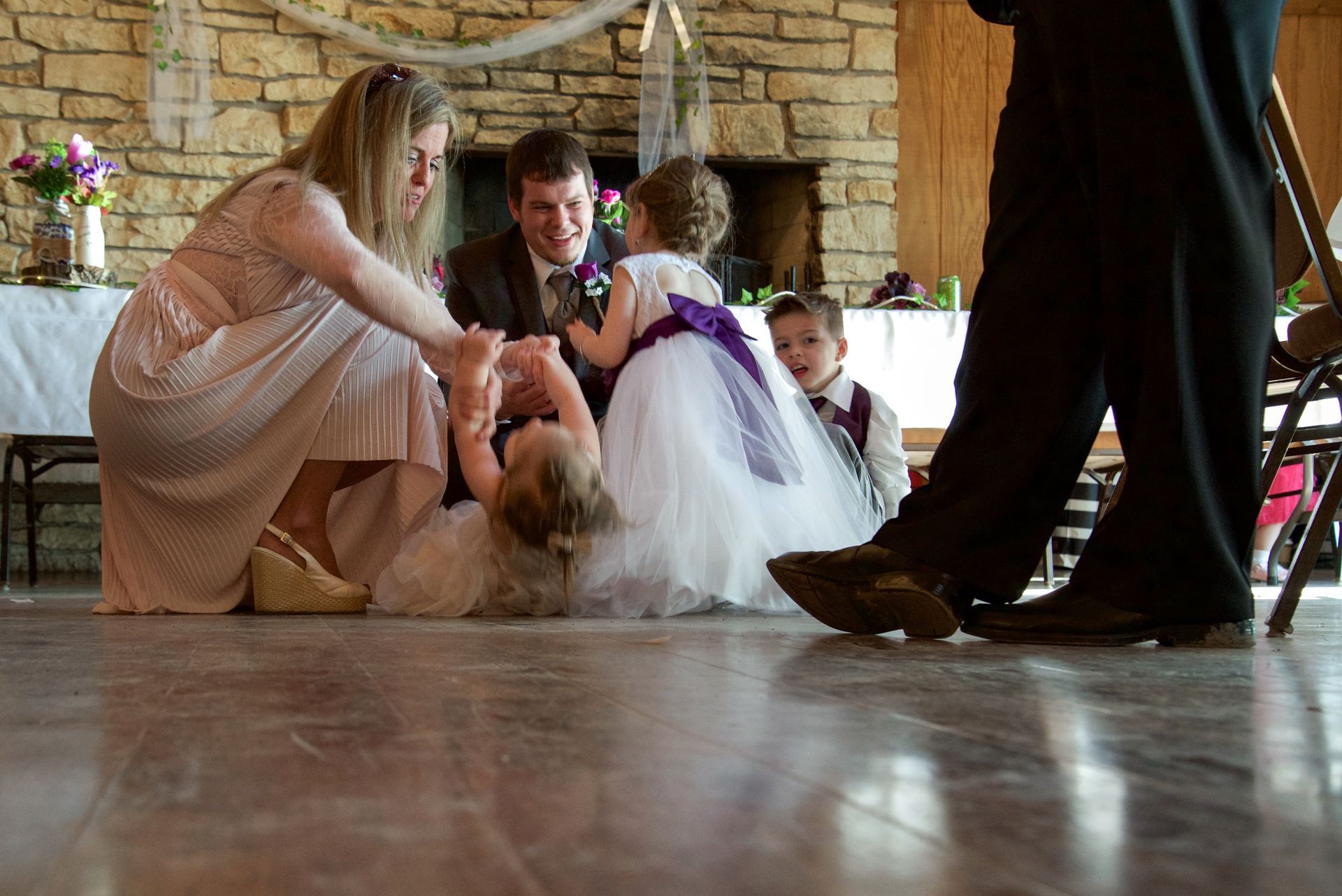 A bride and groom are playing with their children at their wedding reception