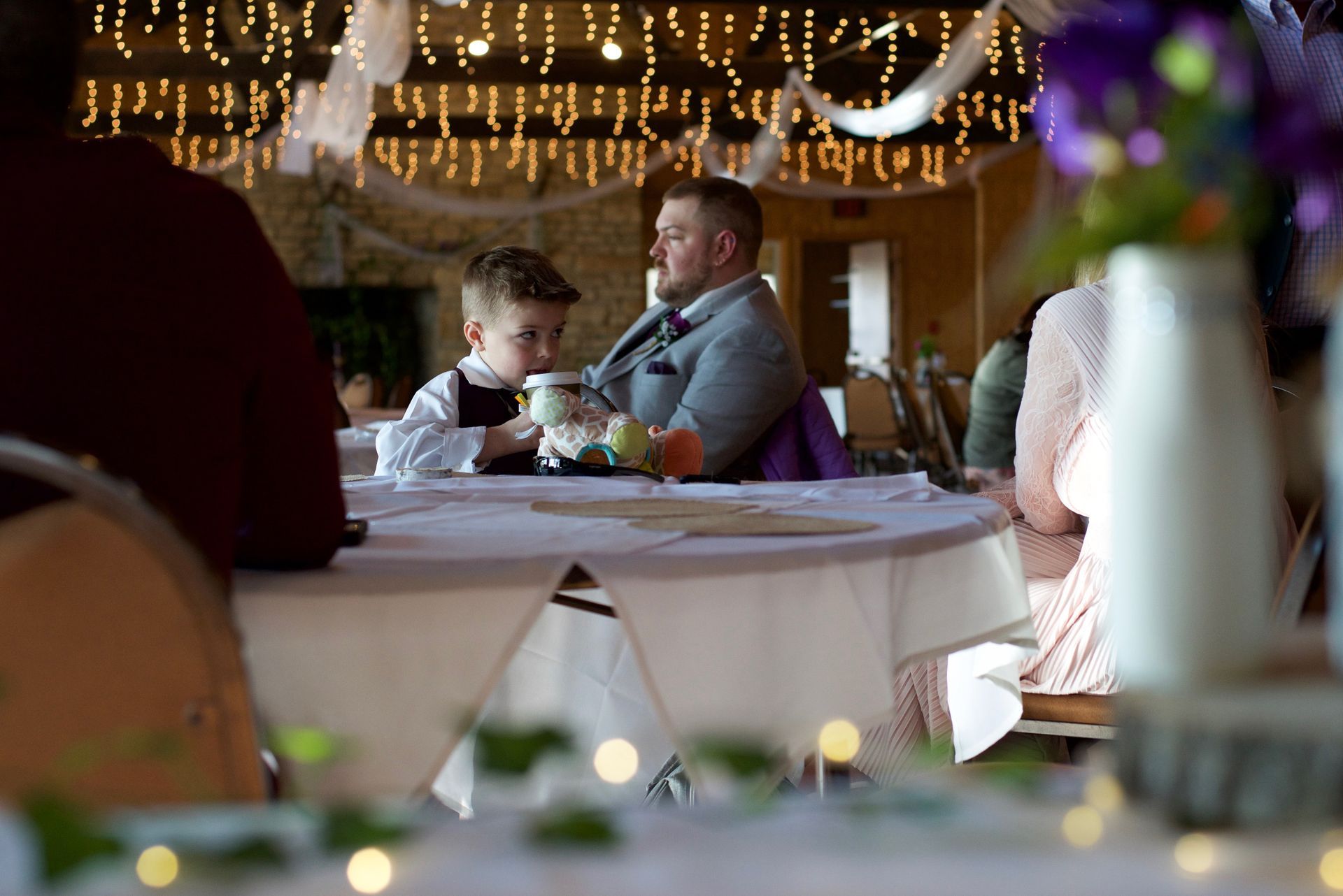A man and a boy sit at a table at a wedding reception