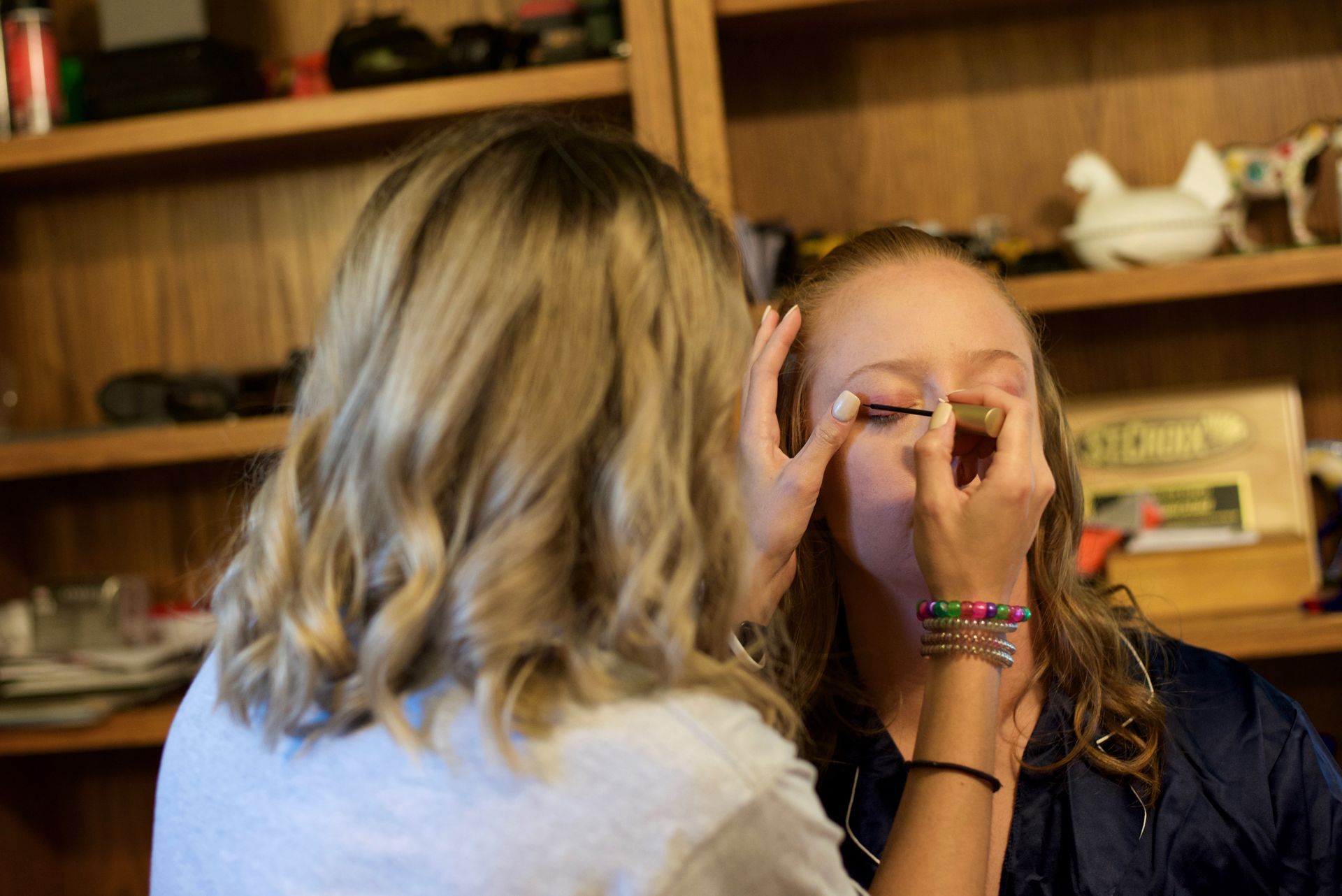 A woman is applying mascara to another woman 's eye