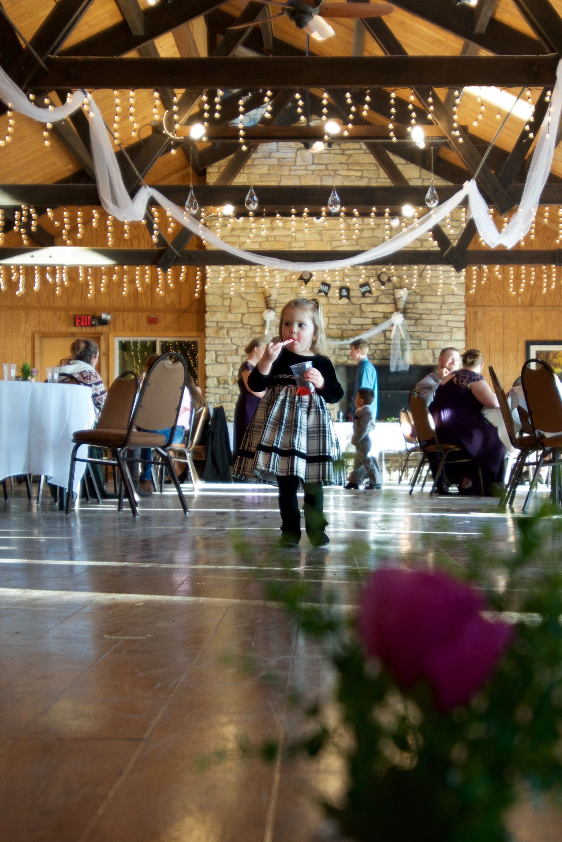 A little girl in a plaid dress is standing on a dance floor