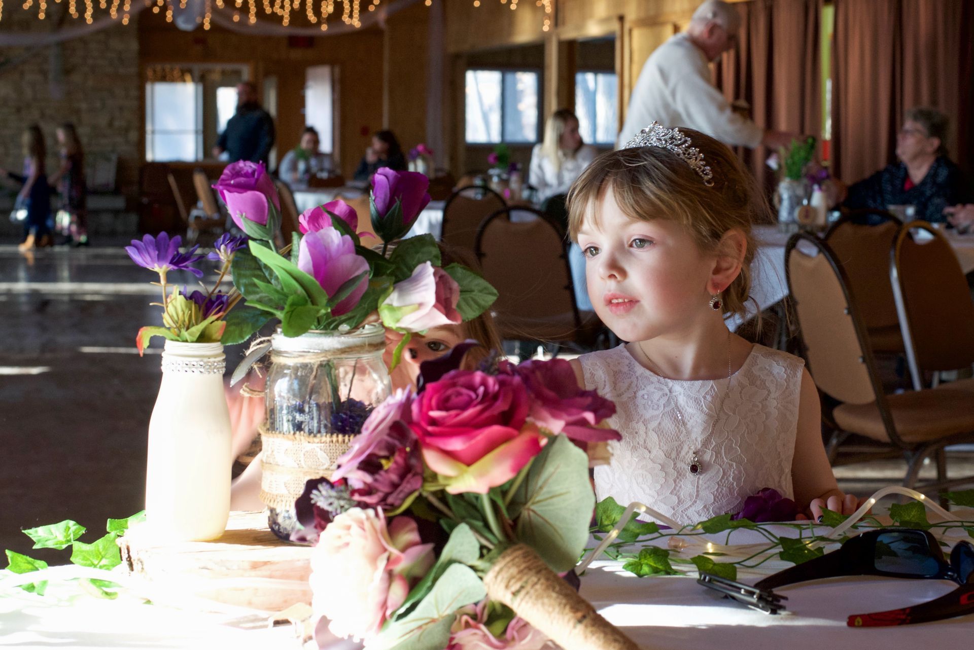A little girl sitting at a table with a bouquet of flowers
