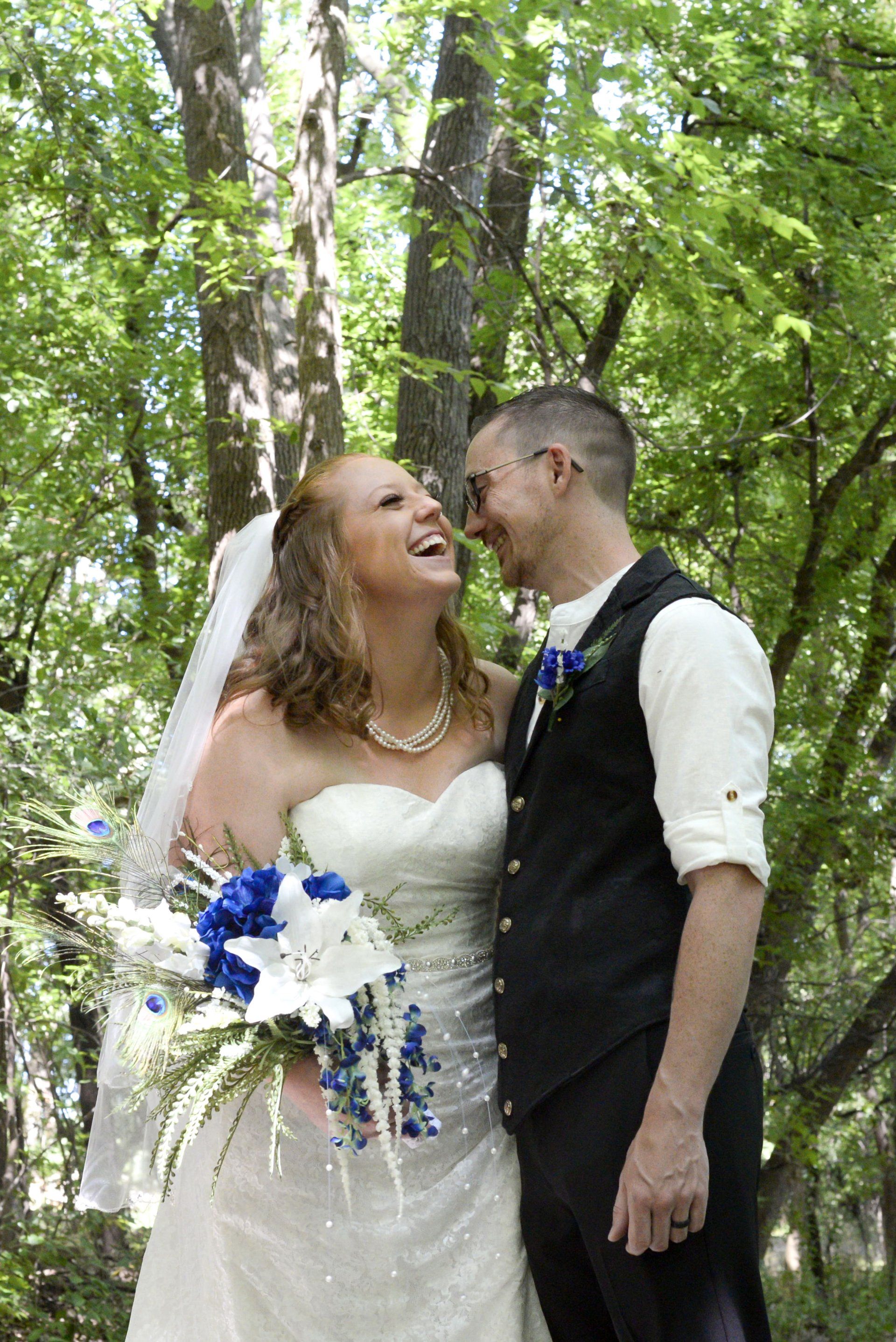 A bride and groom are posing for a picture in the woods