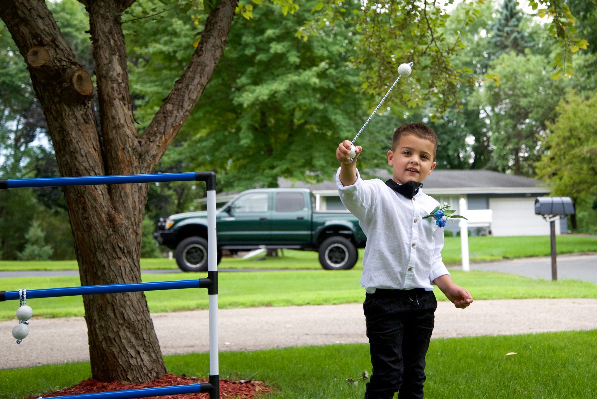 A young boy in a tuxedo is holding a golf club