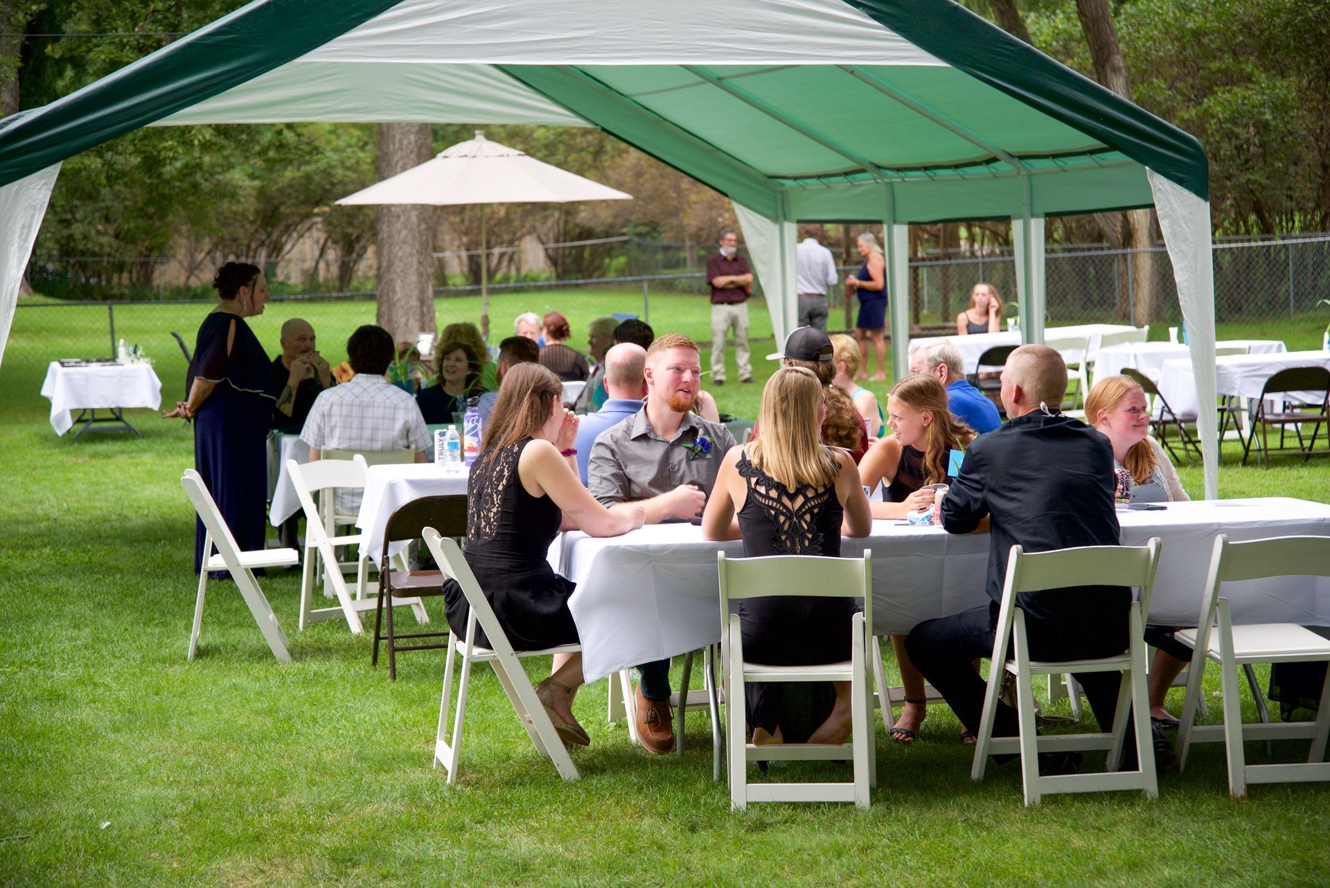 A group of people are sitting at tables under a tent