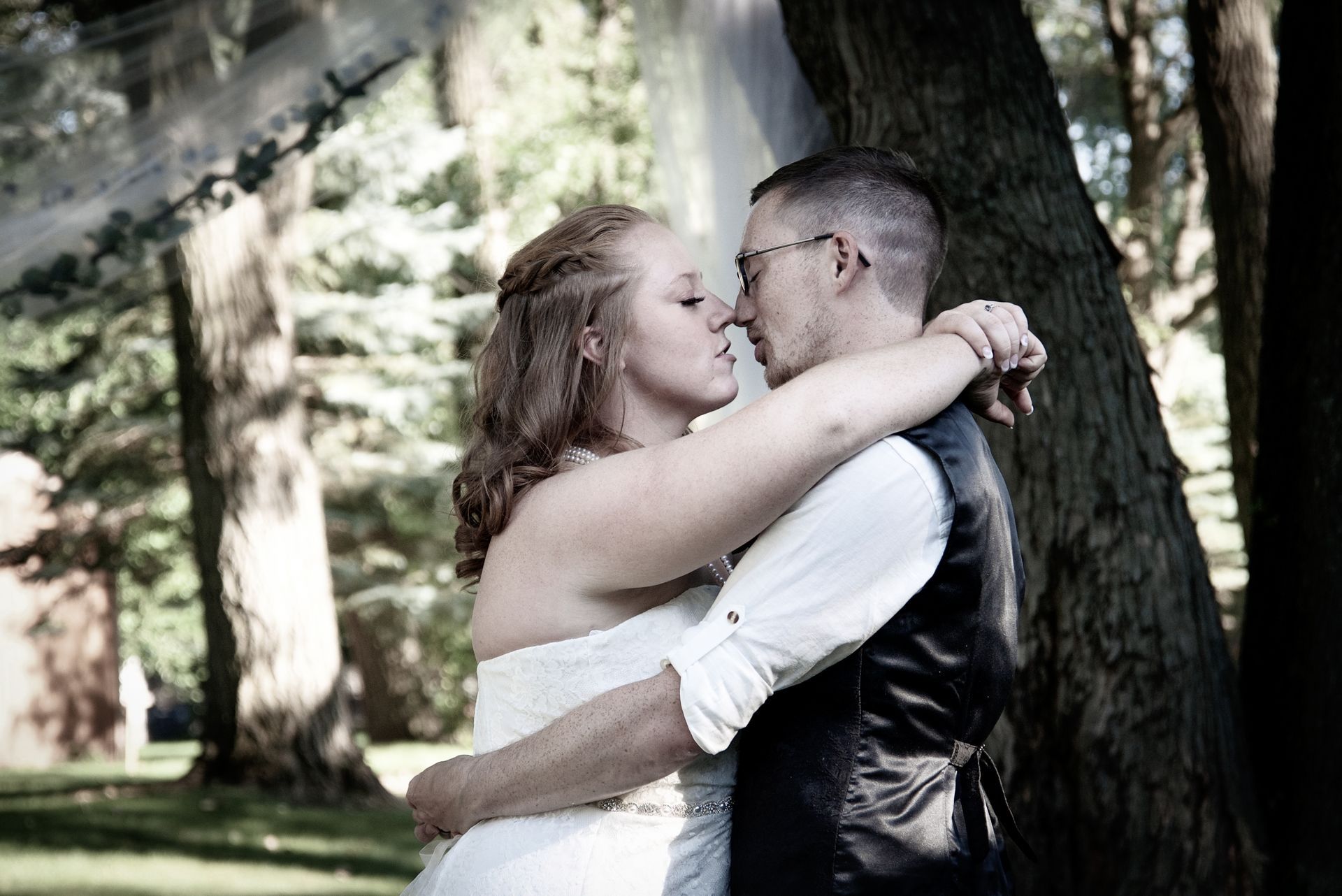 A bride and groom kissing under a canopy in the woods