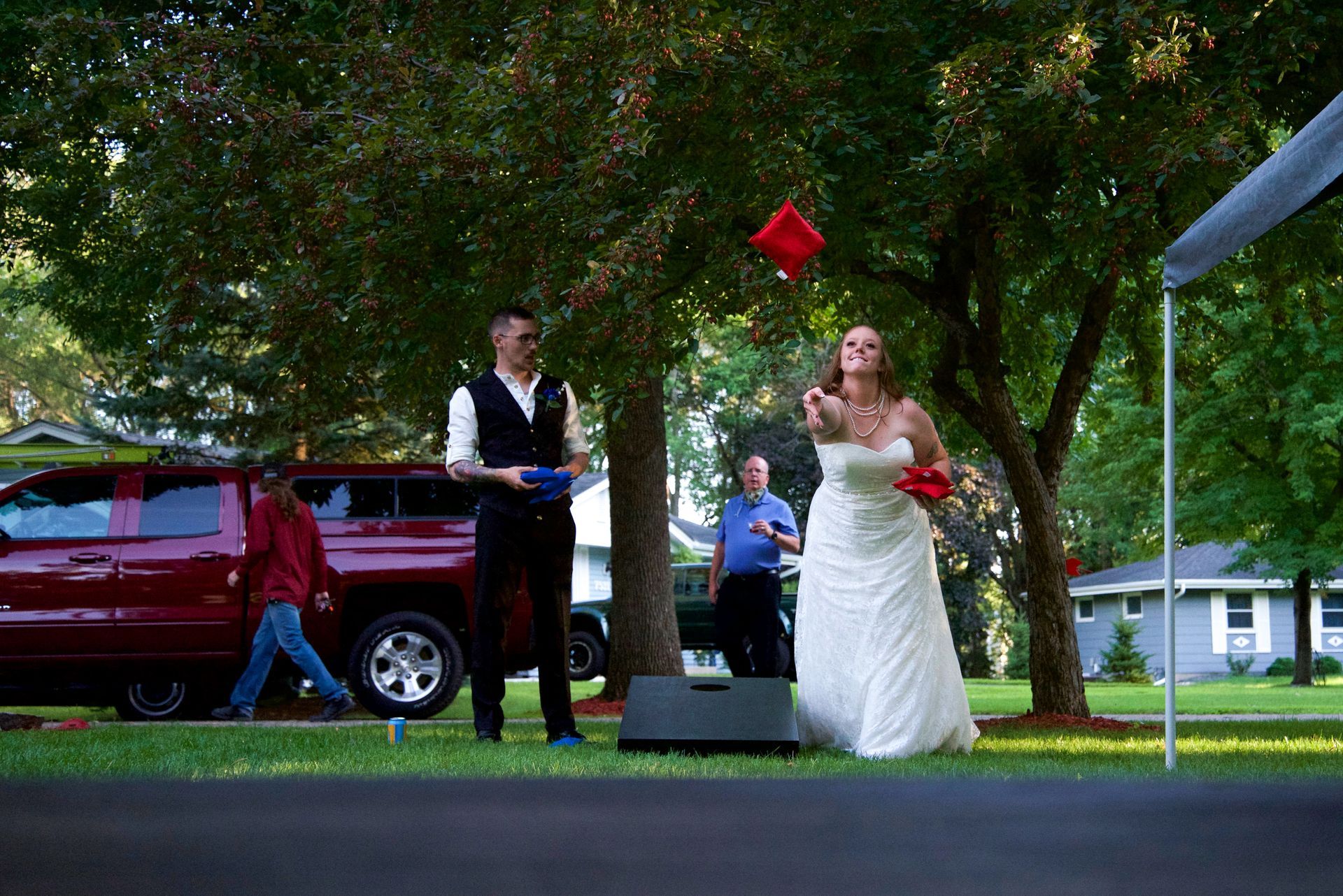 A bride and groom are throwing a red pillow in the air