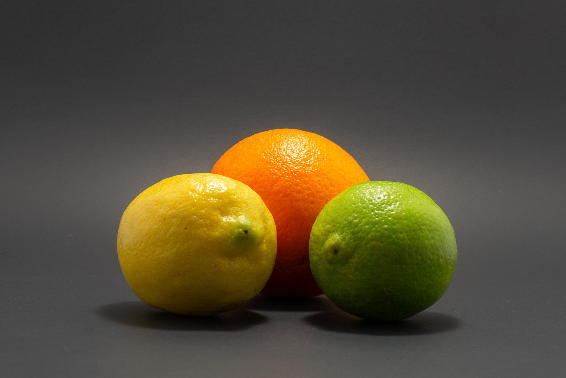 A lemon an orange and a lime on a black background