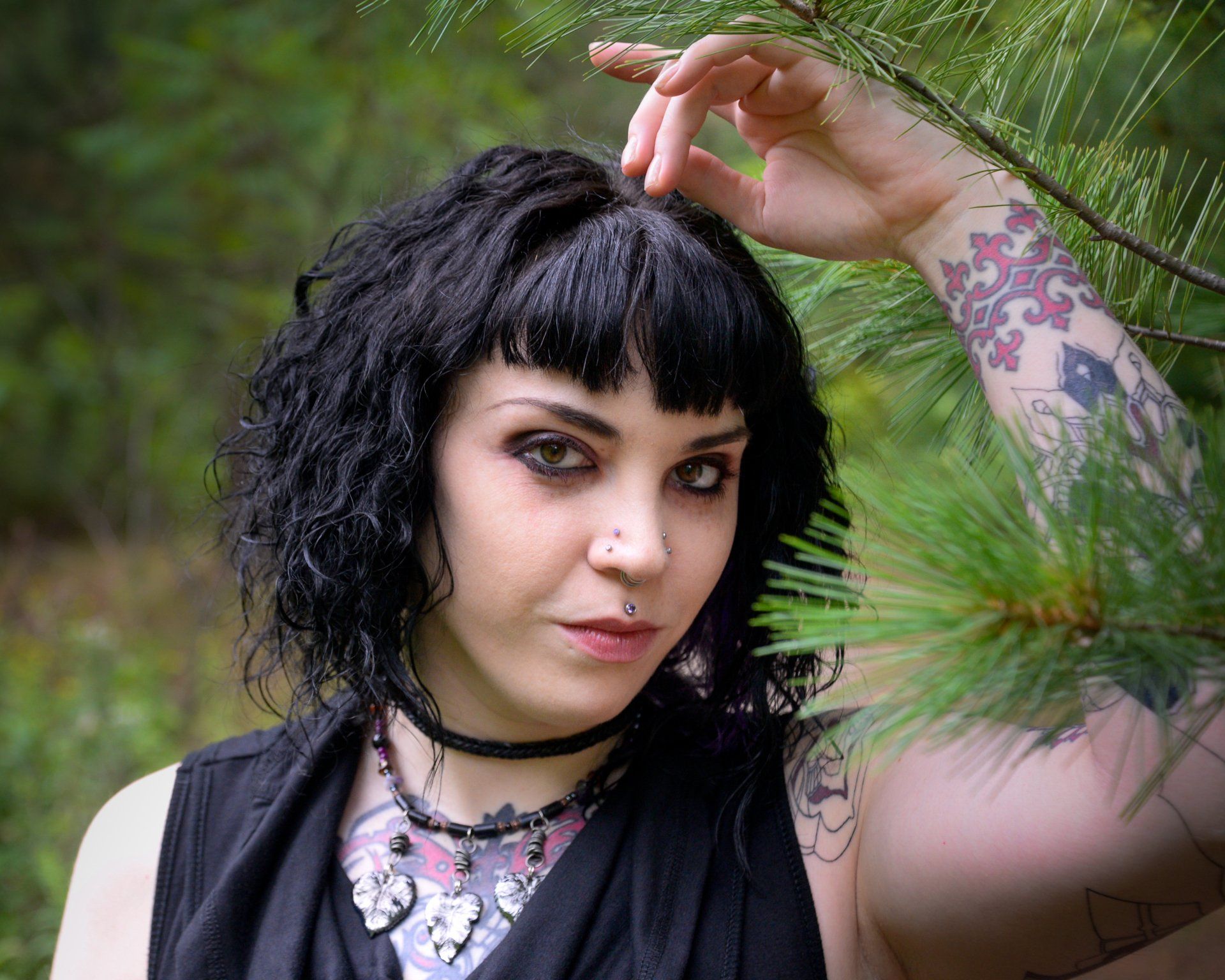A woman with a tattoo on her arm is touching her hair