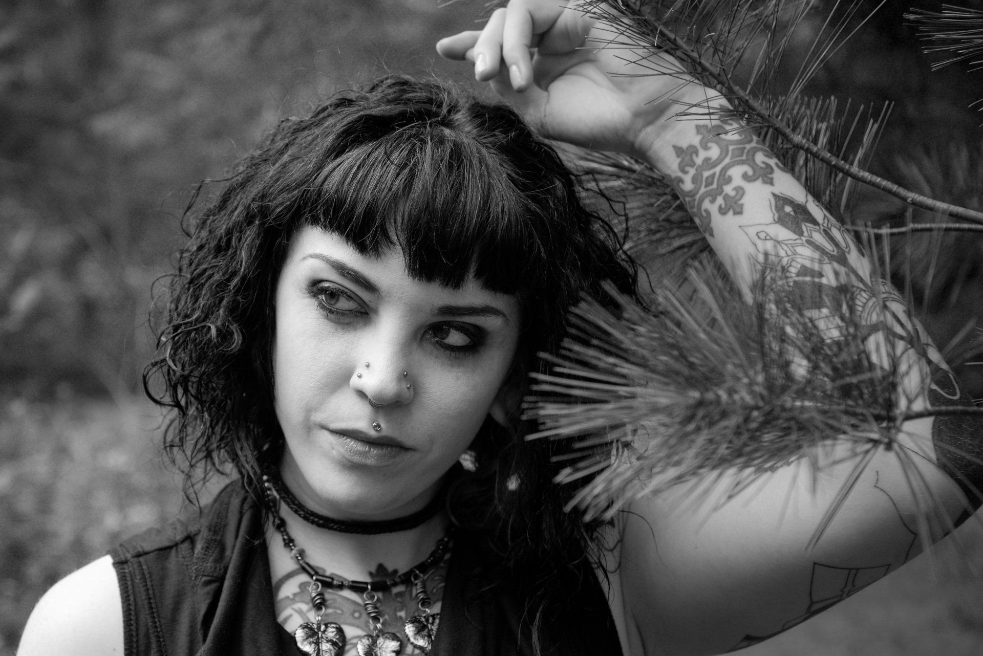 A black and white photo of a woman with a tattoo on her arm.