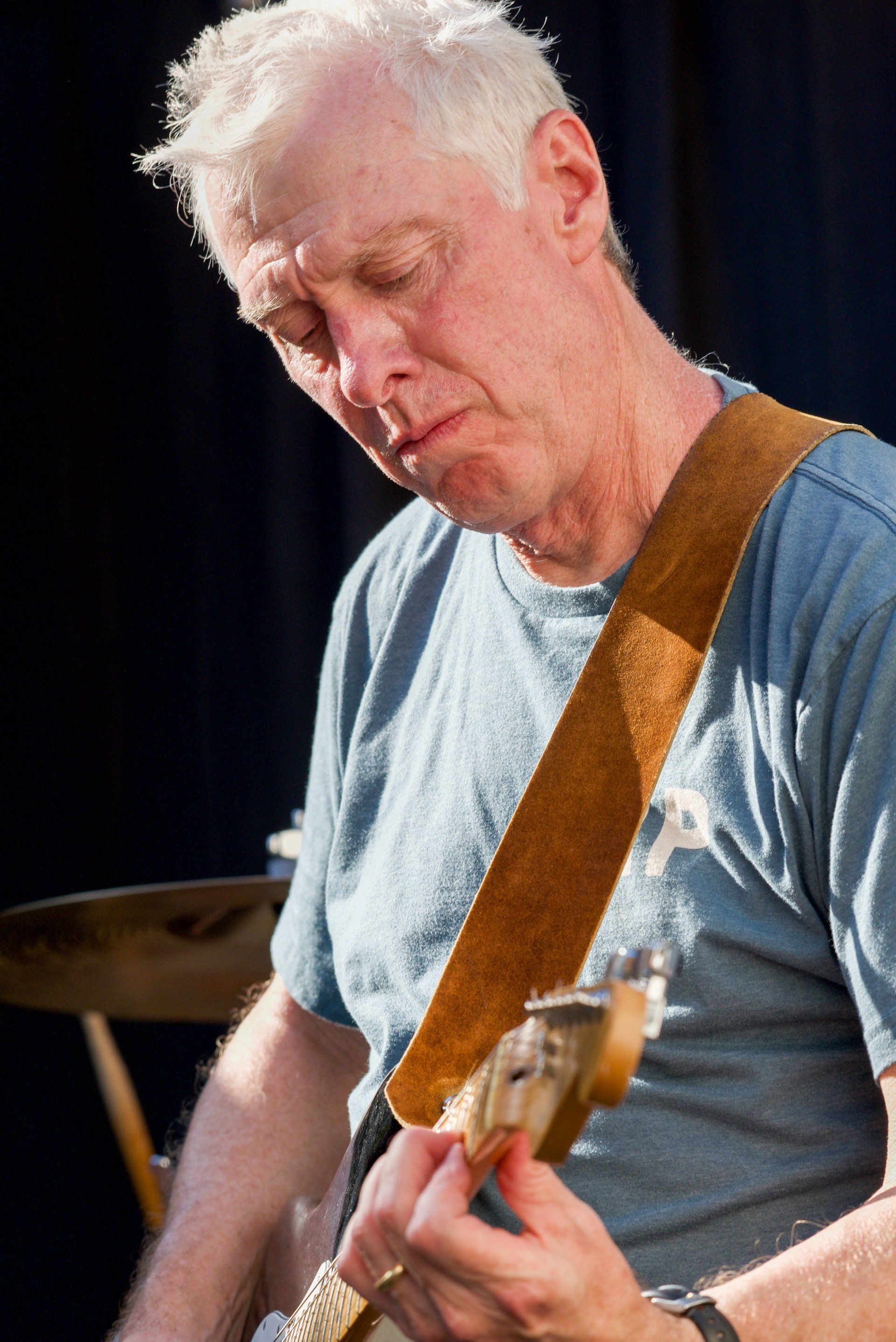 A man in a blue shirt is playing a guitar