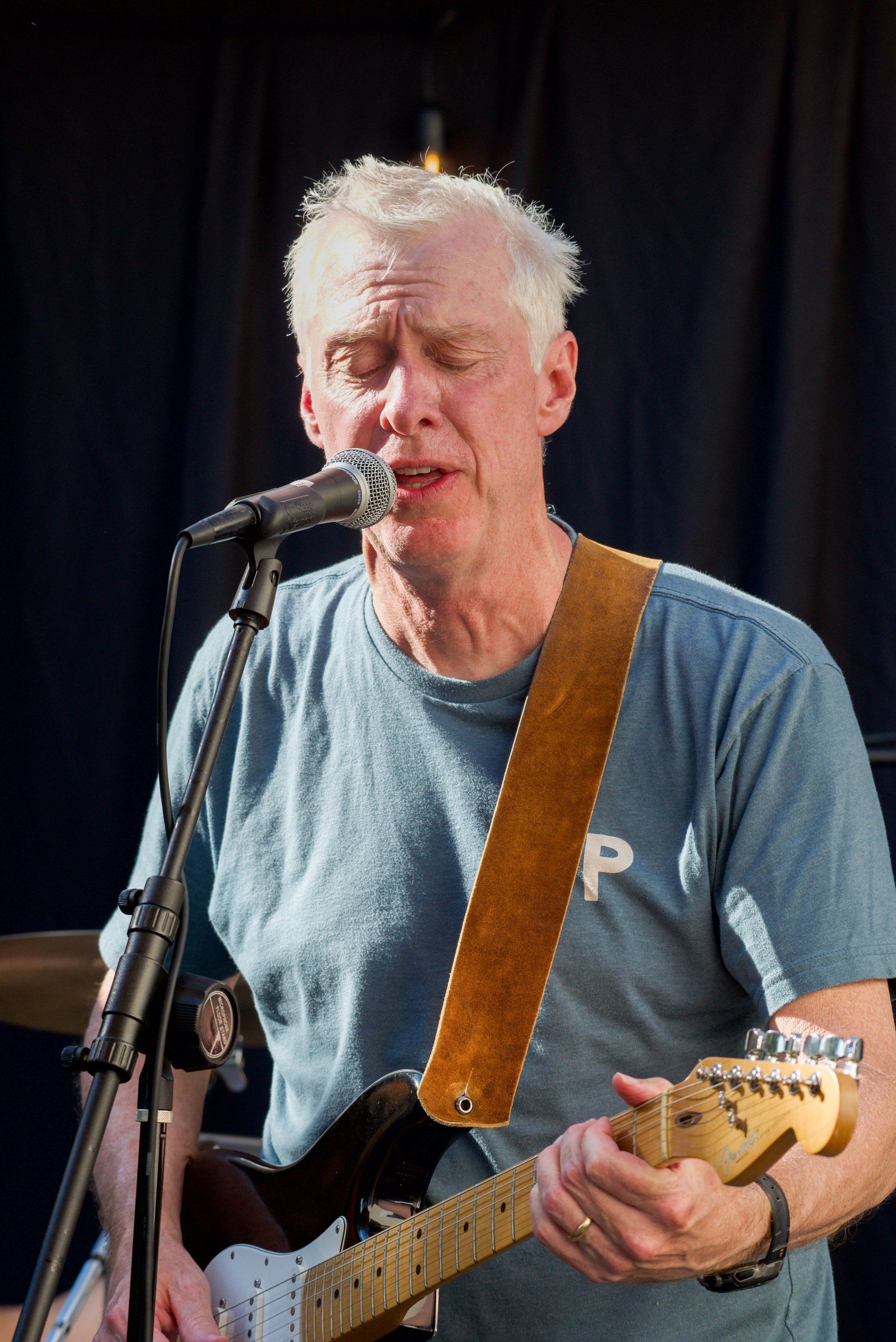A man singing into a microphone while playing a guitar