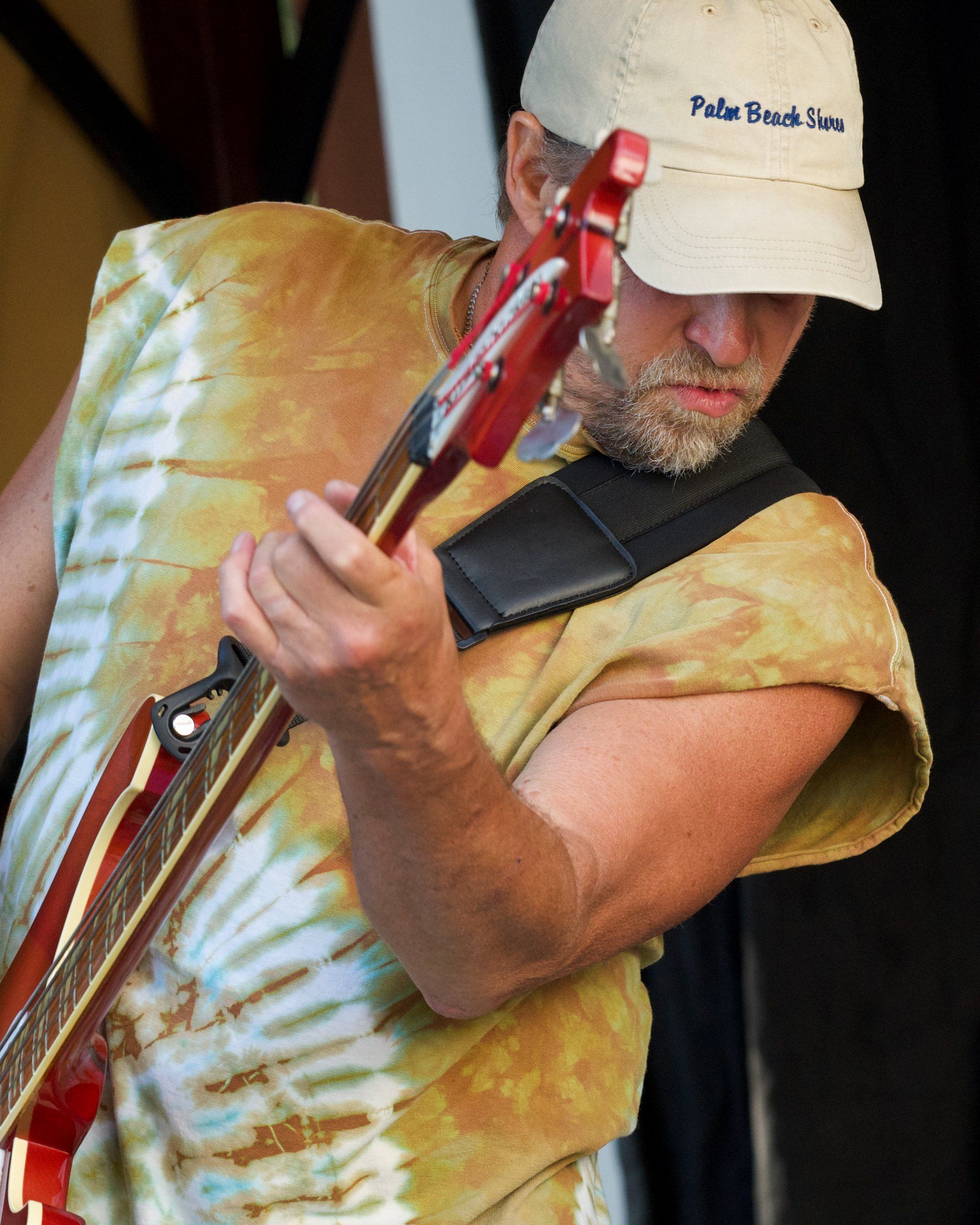 A man is playing a guitar and wearing a hat that says peter burg shin