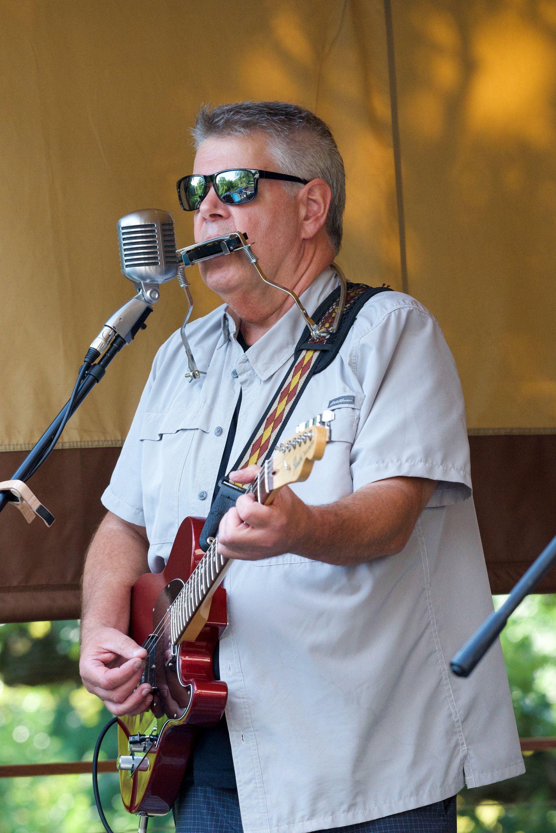 A man singing into a microphone while playing a guitar