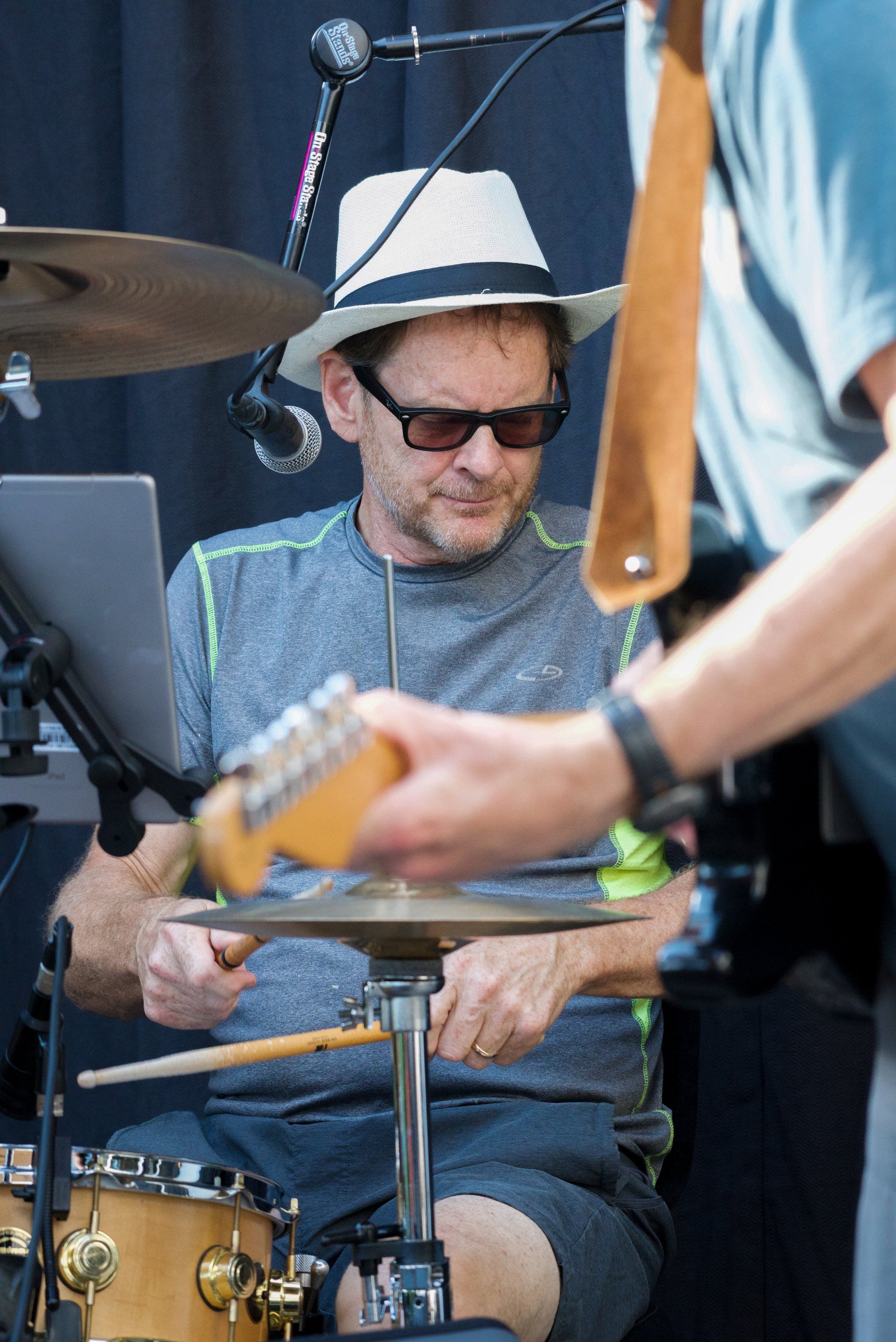 A man wearing a hat and sunglasses is playing drums
