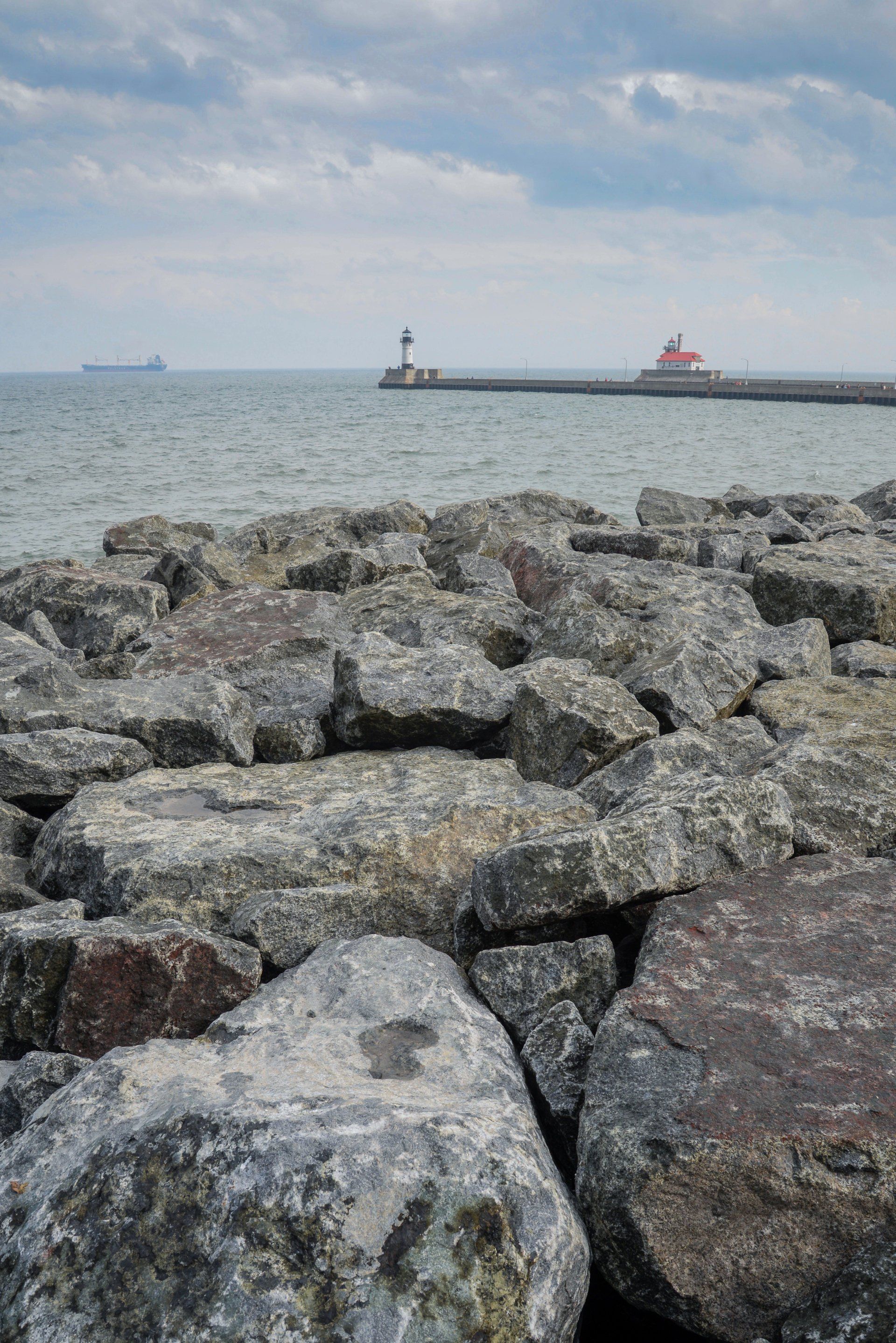 A rocky shoreline with a lighthouse in the distance