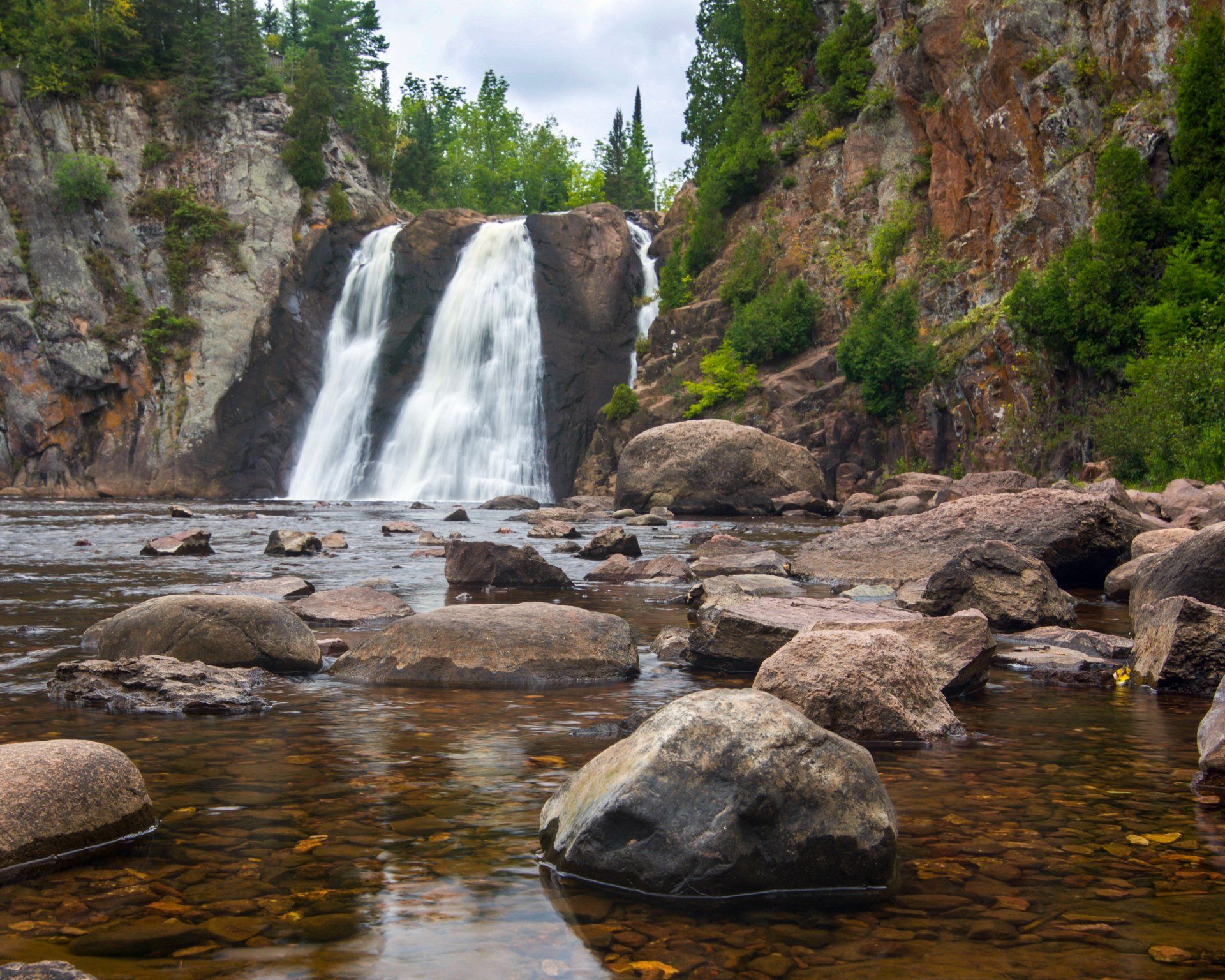 A waterfall is surrounded by rocks and trees