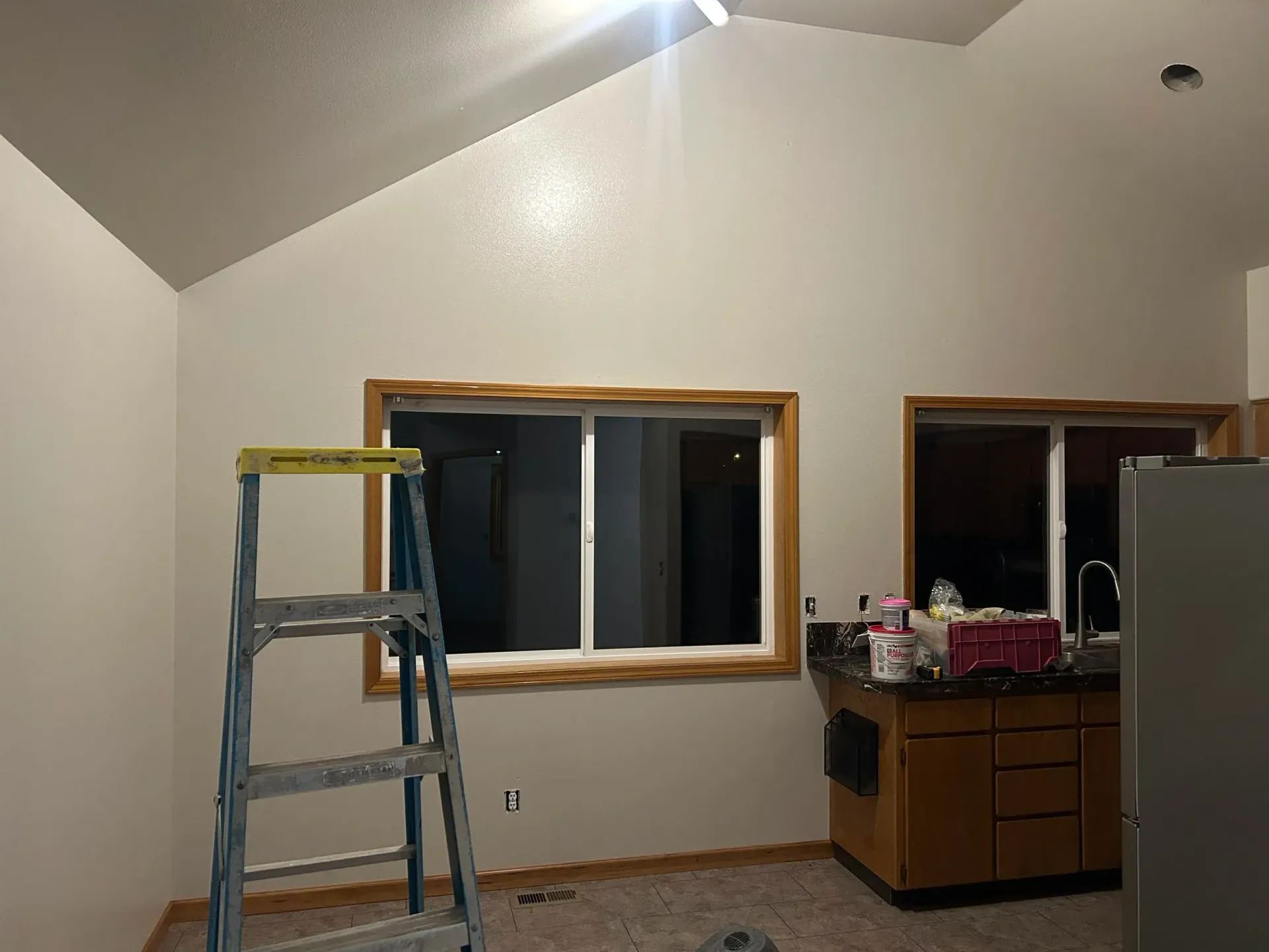 Interior room with a ladder, windows, and cabinets. The walls and ceiling are white.