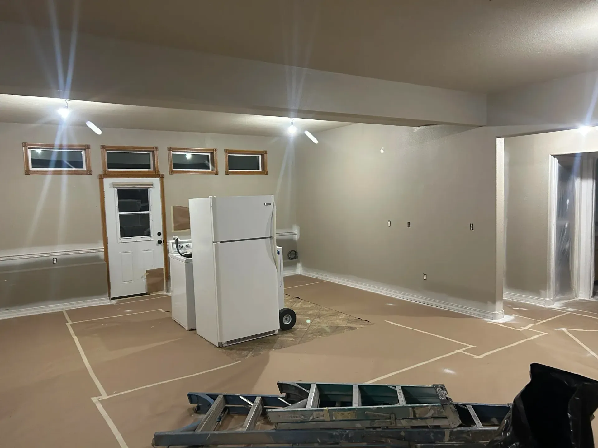 Interior renovation: room with appliances, masking tape on floor, paint prep.