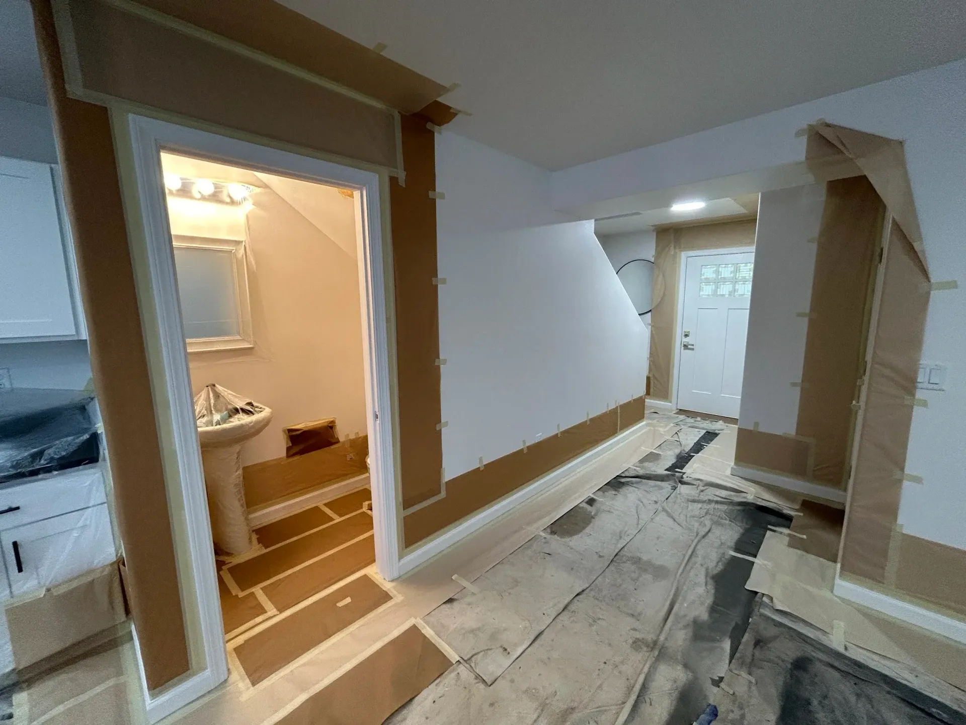 Room under renovation with cardboard covering walls and floors, doorway to a bathroom.