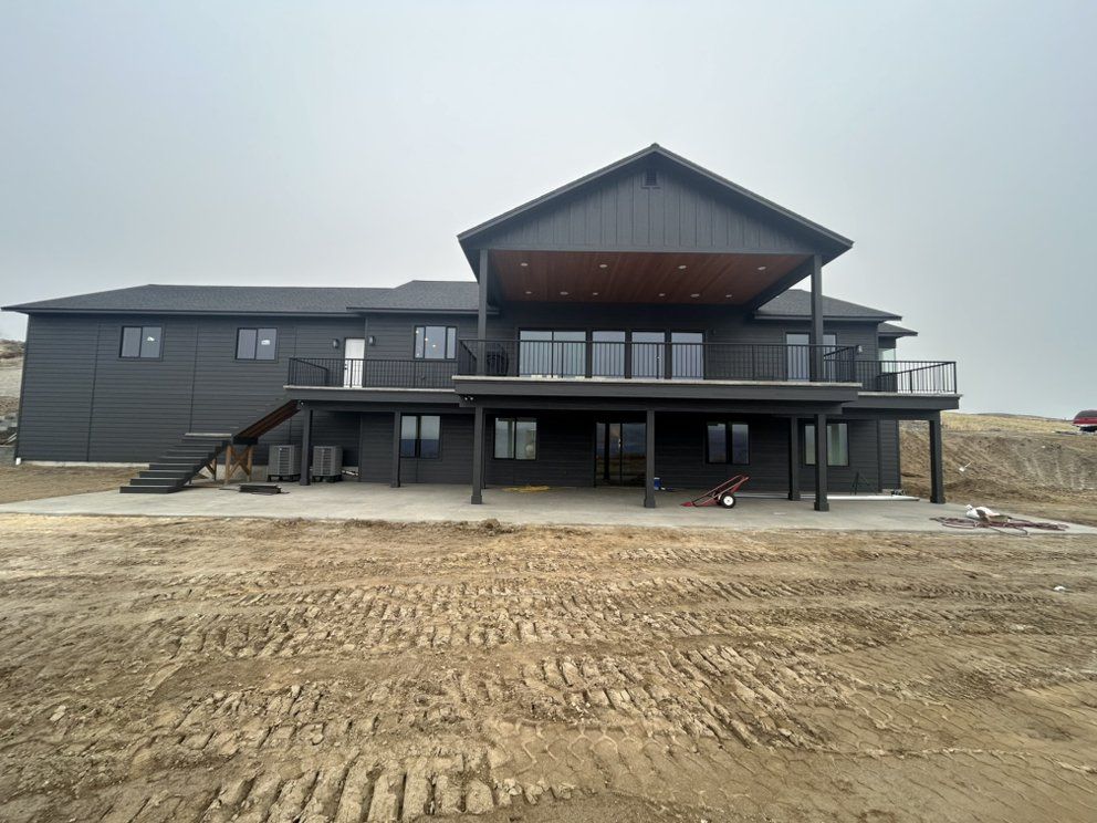 Dark gray house with a deck under a cloudy sky. Construction site.