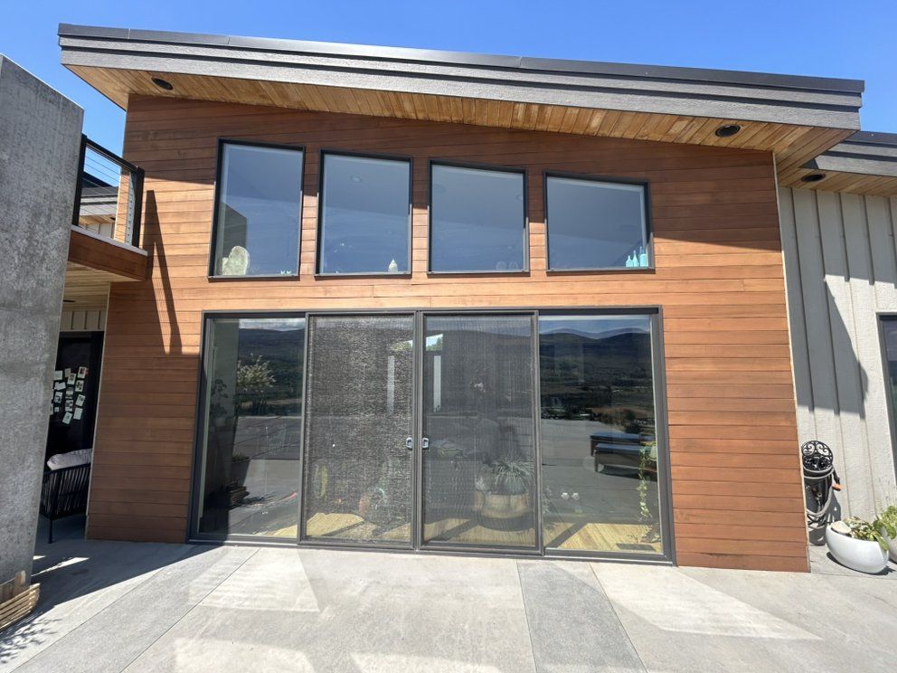 Modern building with brown siding and large windows, door. Exterior view.