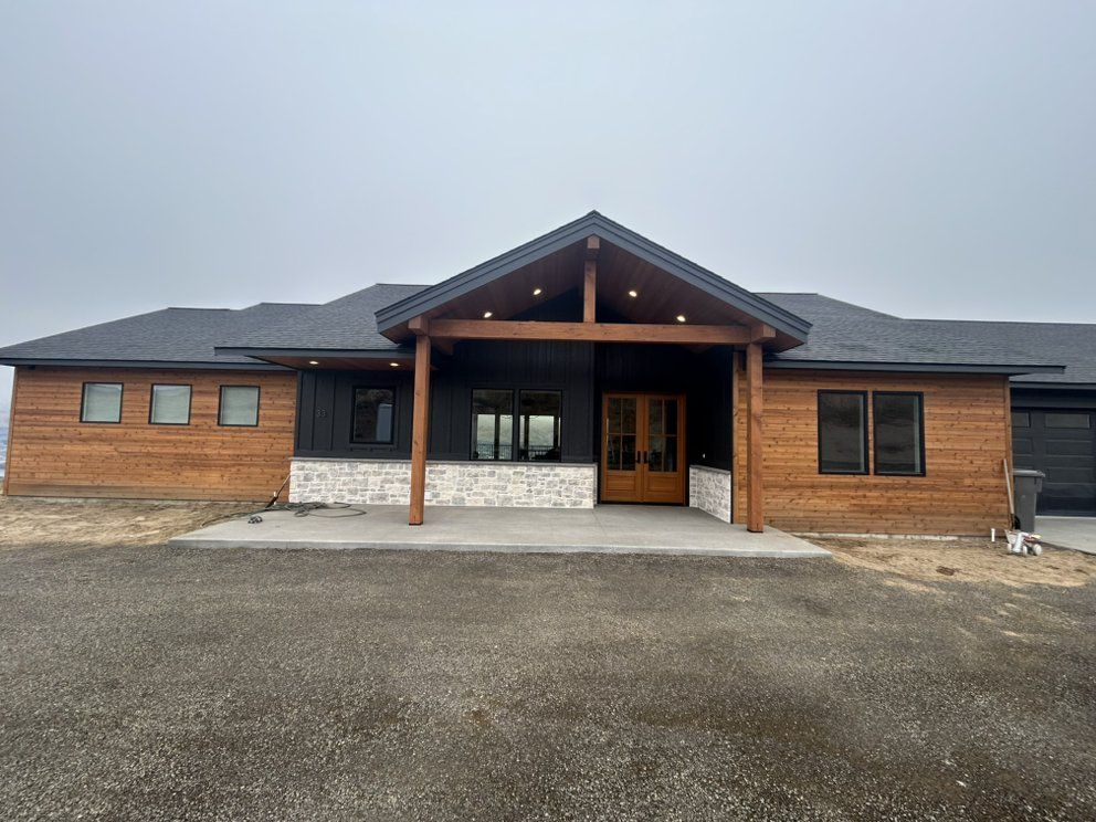 Modern house with wooden siding, black accents, and covered entrance on a cloudy day.