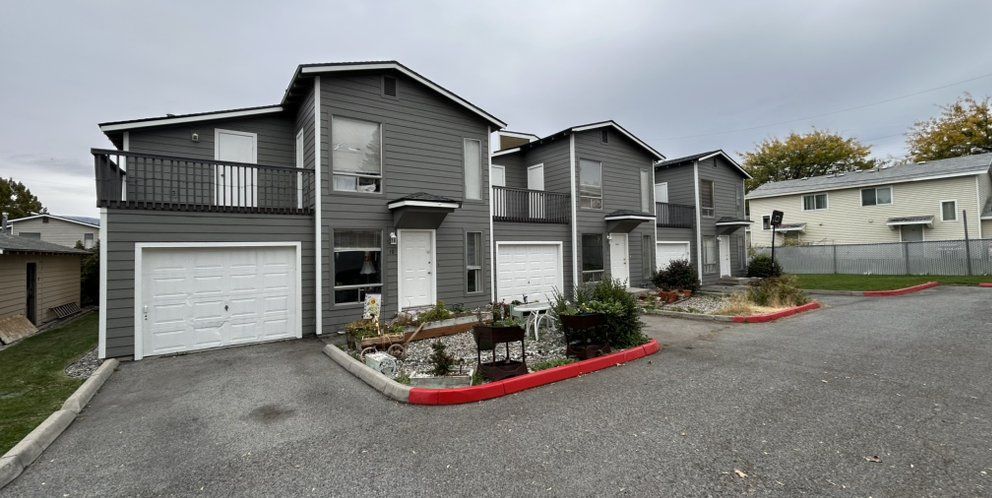 Gray townhomes with white garage doors and a red curb.